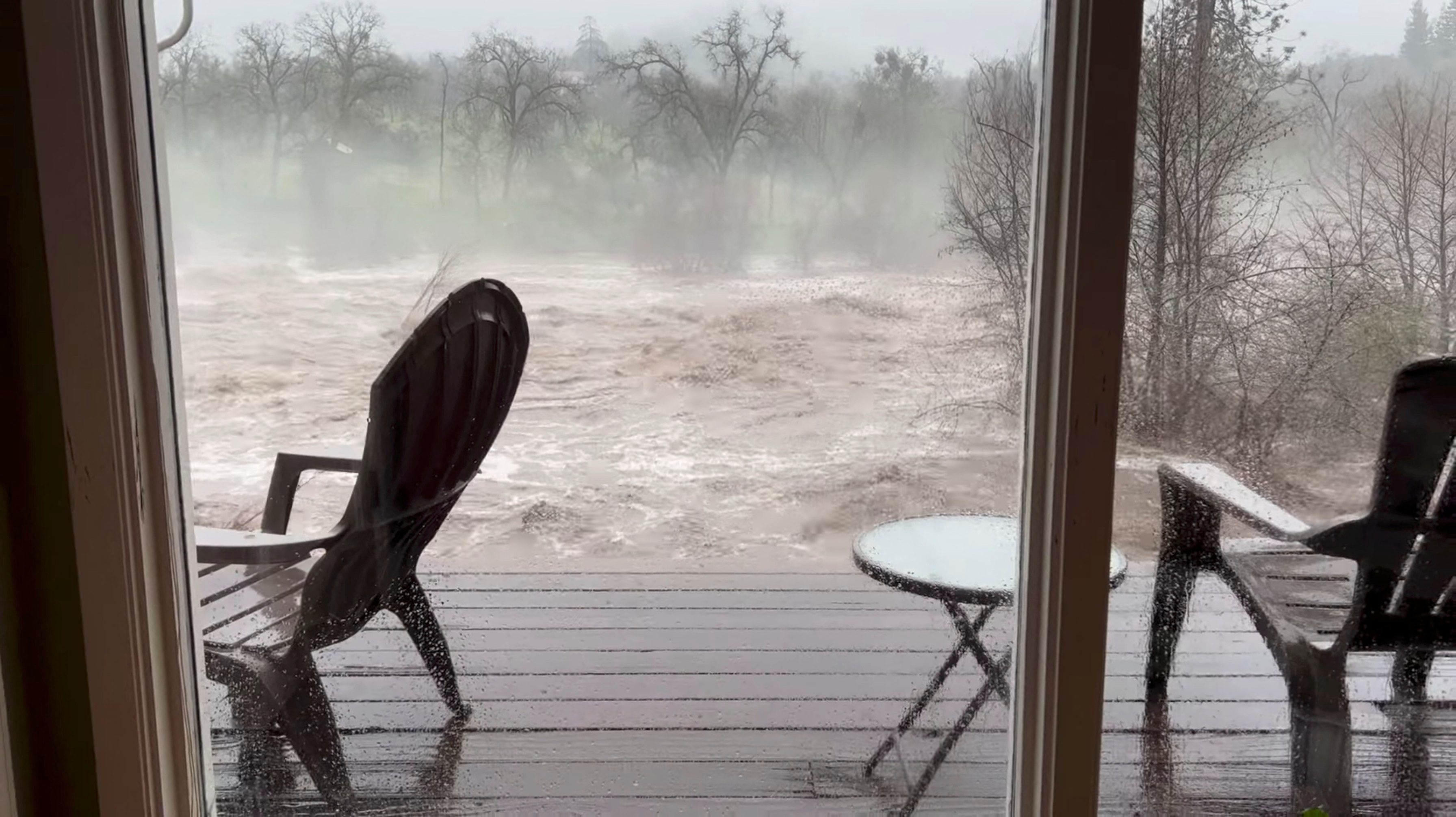 A view shows the overflowing Kern River, as seen from the living room window of a person's house, in Three Rivers