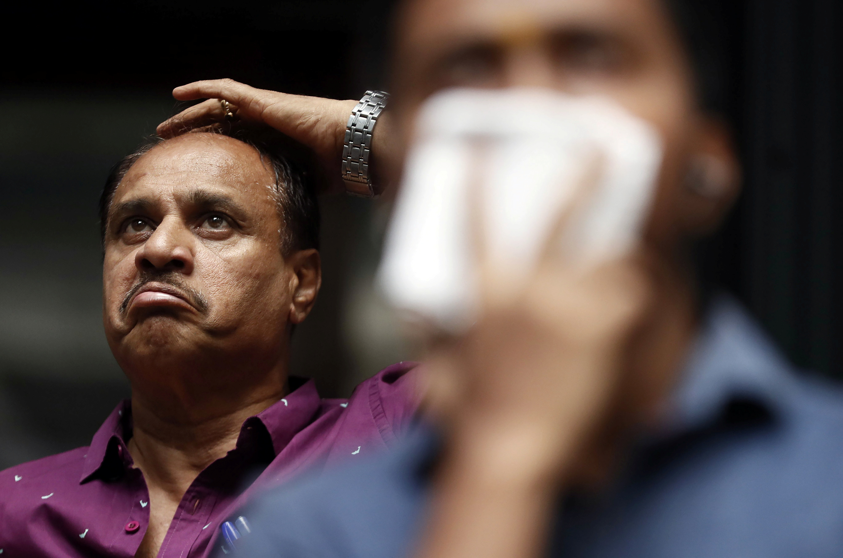 Man reacts as he looks at screen displaying Sensex results on BSE building in Mumbai