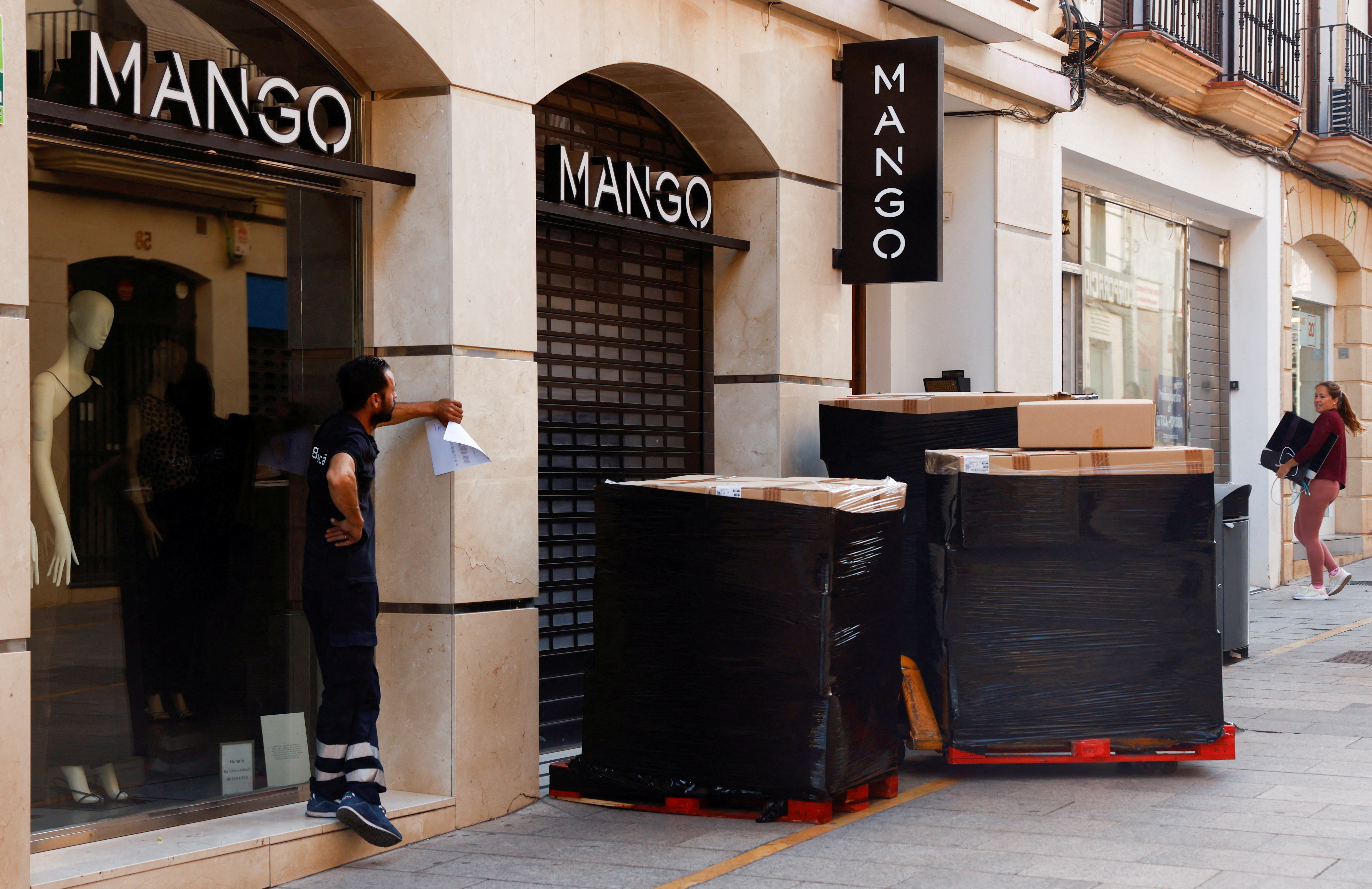 A delivery worker waits for the opening of a store of Spanish fashion chain Mango in Ronda