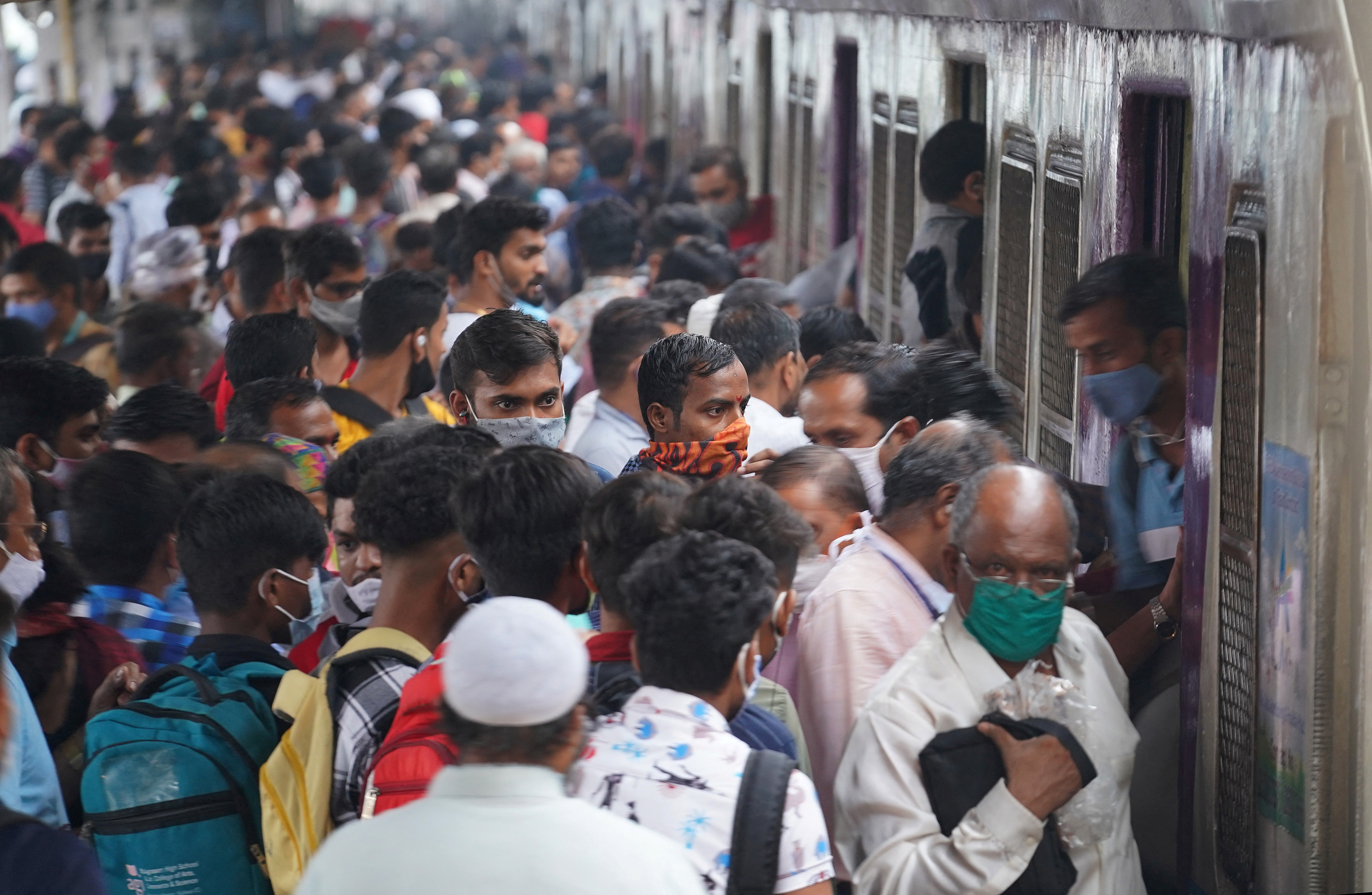Commuters disembark from a suburban train at a railway station in Mumbai