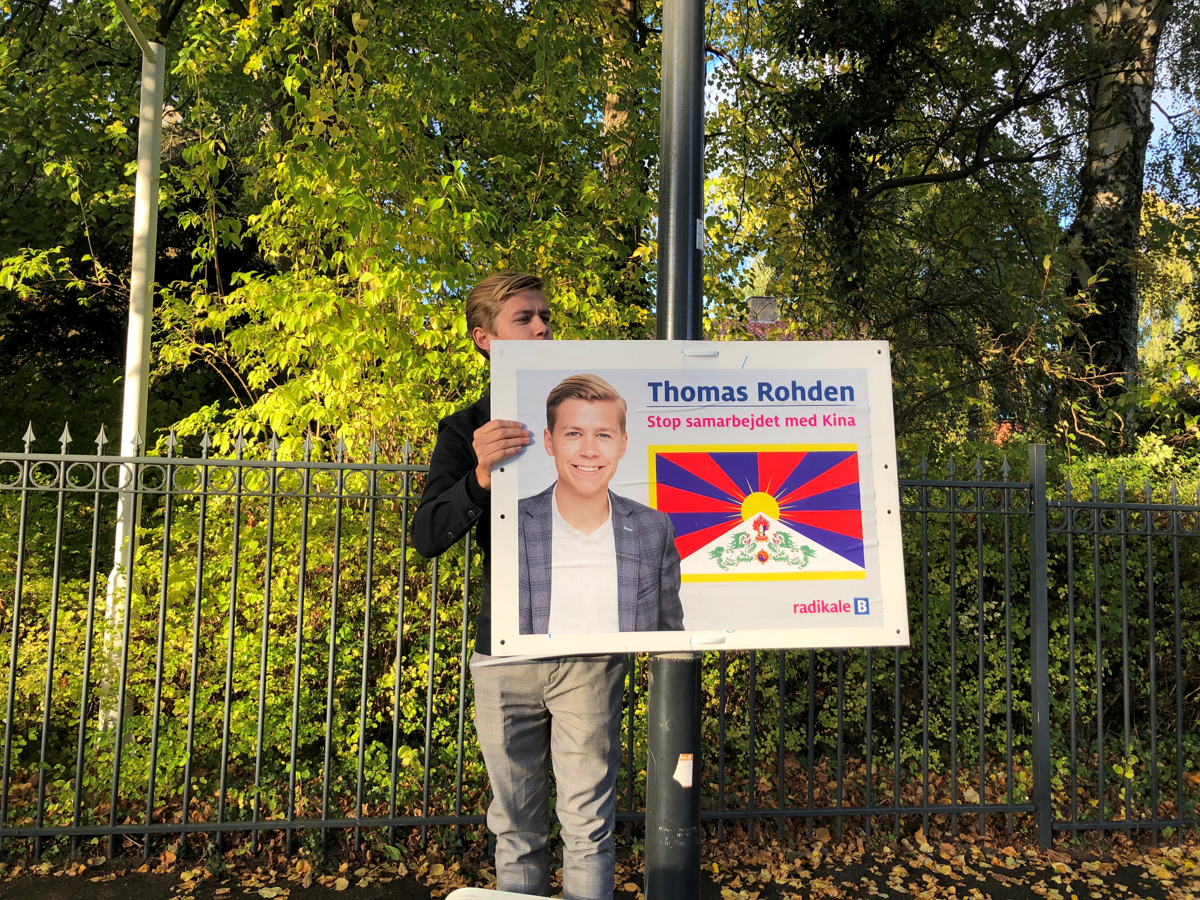 Political candidate in upcoming local elections Thomas Rohden hangs up posters displaying him next to a Tibetan flag outside the Chinese embassy near Copenhagen