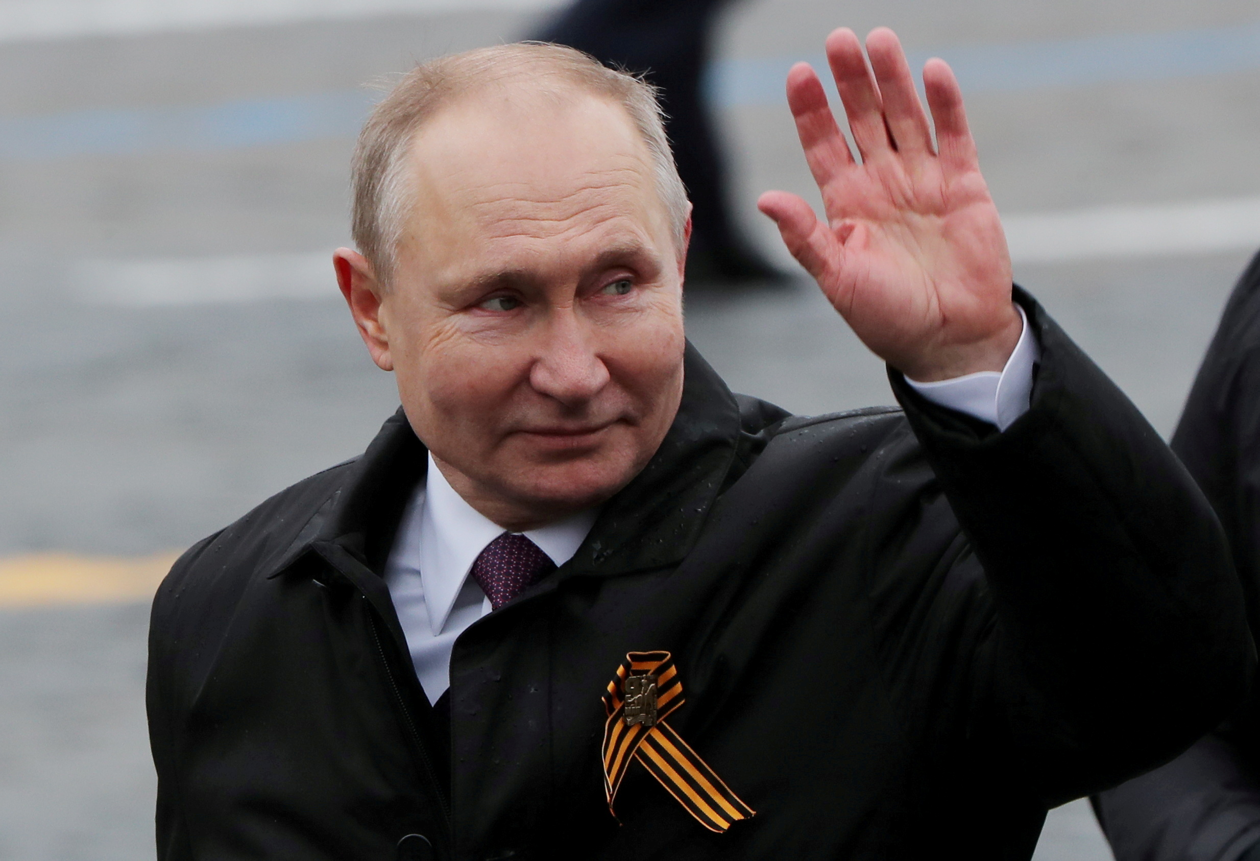 Russian President Vladimir Putin waves while walking along Red Square in Moscow