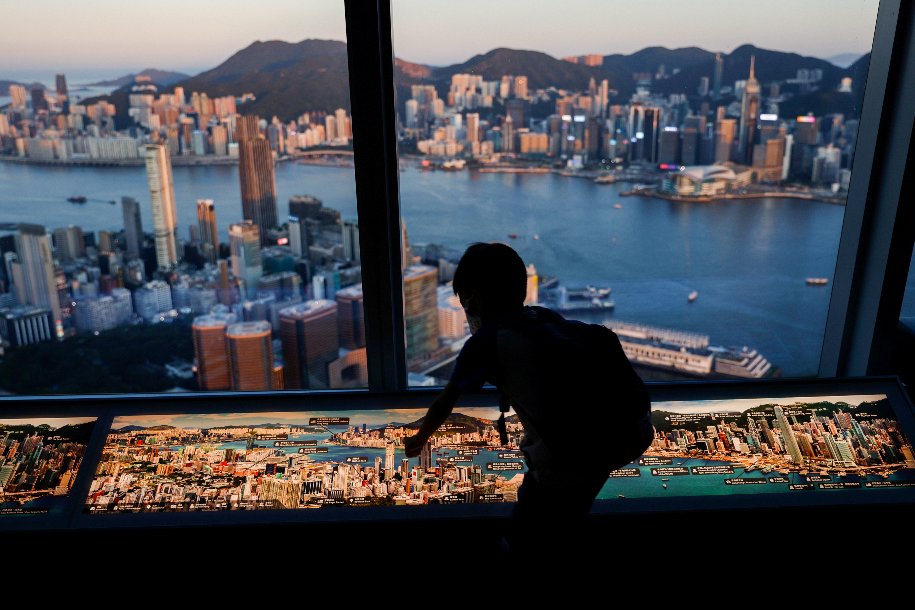 A child plays in front of skyline buildings, in Hong Kong