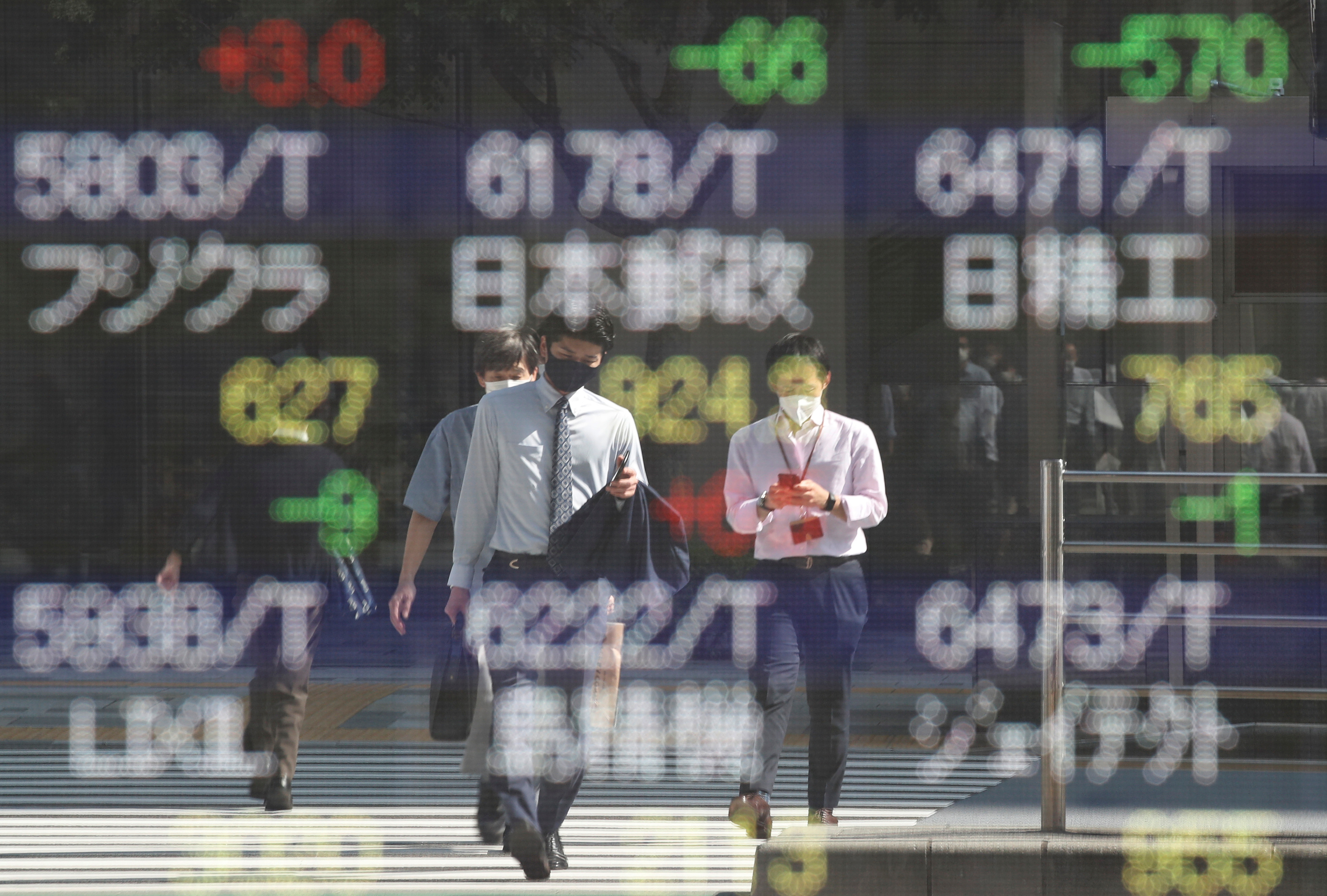 People wearing protective masks, amid the coronavirus disease (COVID-19) outbreak, are reflected on an electronic board displaying Japan's stock prices outside a brokerage in Tokyo, Japan, October 5, 2021. REUTERS/Kim Kyung-Hoon