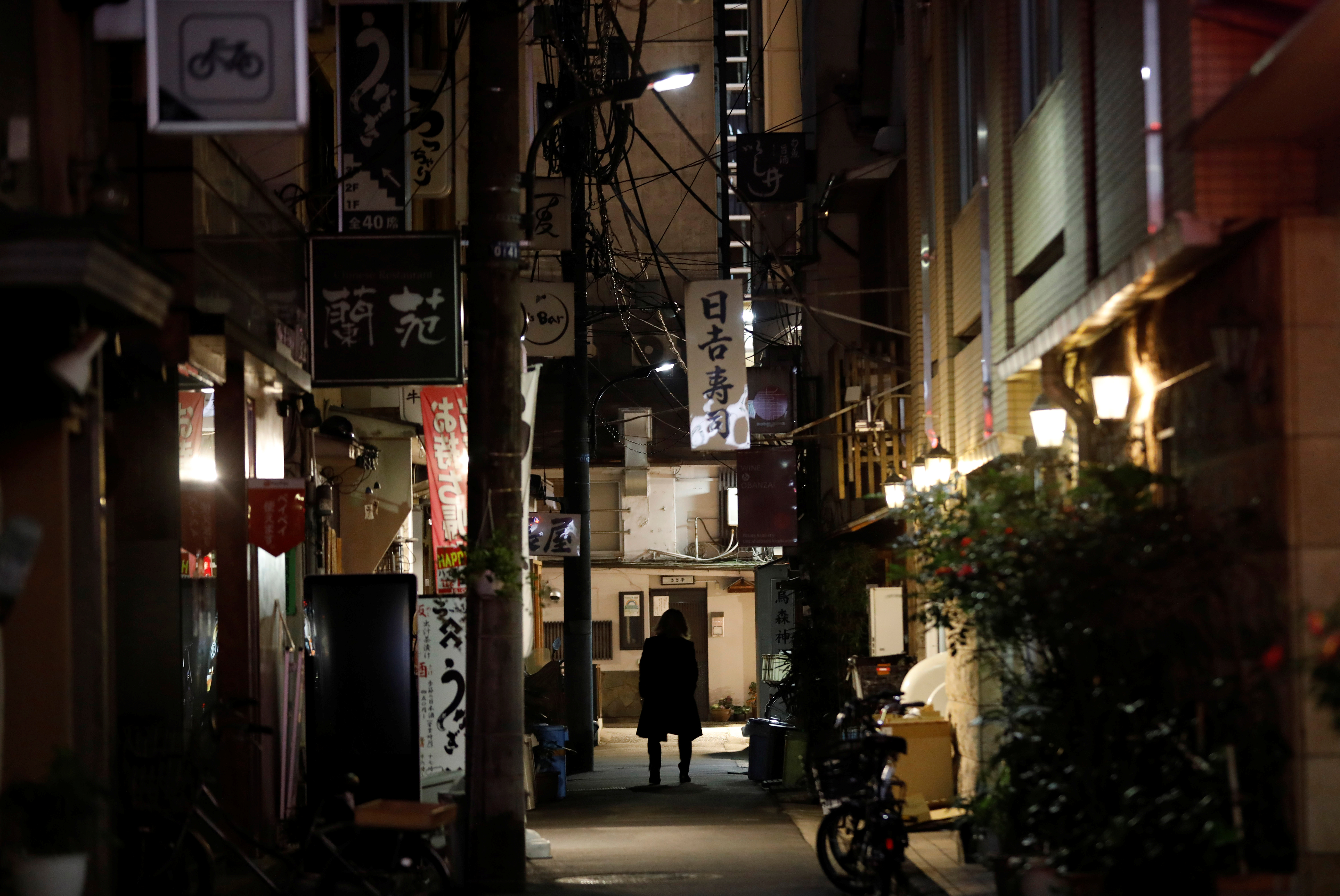 A man walks past restaurants which closed after 8 PM, the time the government asks them to close by, amid the coronavirus emergency decree in Tokyo, Japan, January 15, 2021.REUTERS/Kim Kyung-Hoon