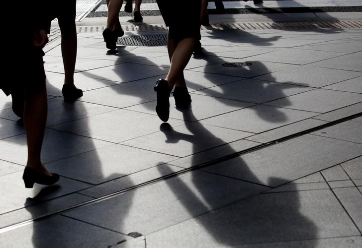 Female office workers wearing high heels and clothes of the same colour walk at a business district in Tokyo