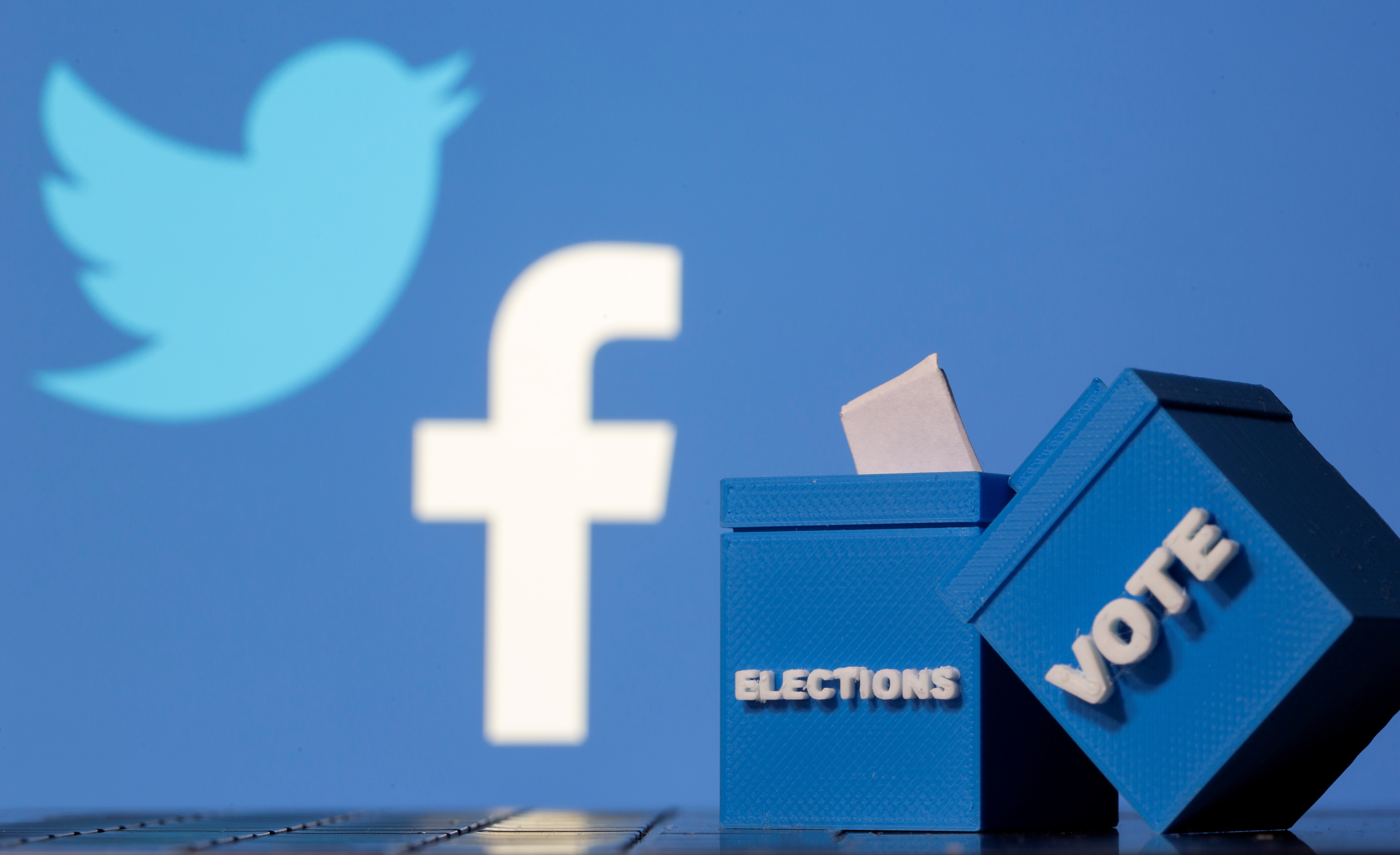 3D-printed ballot boxes are seen in front of Facebook and Twitter logos