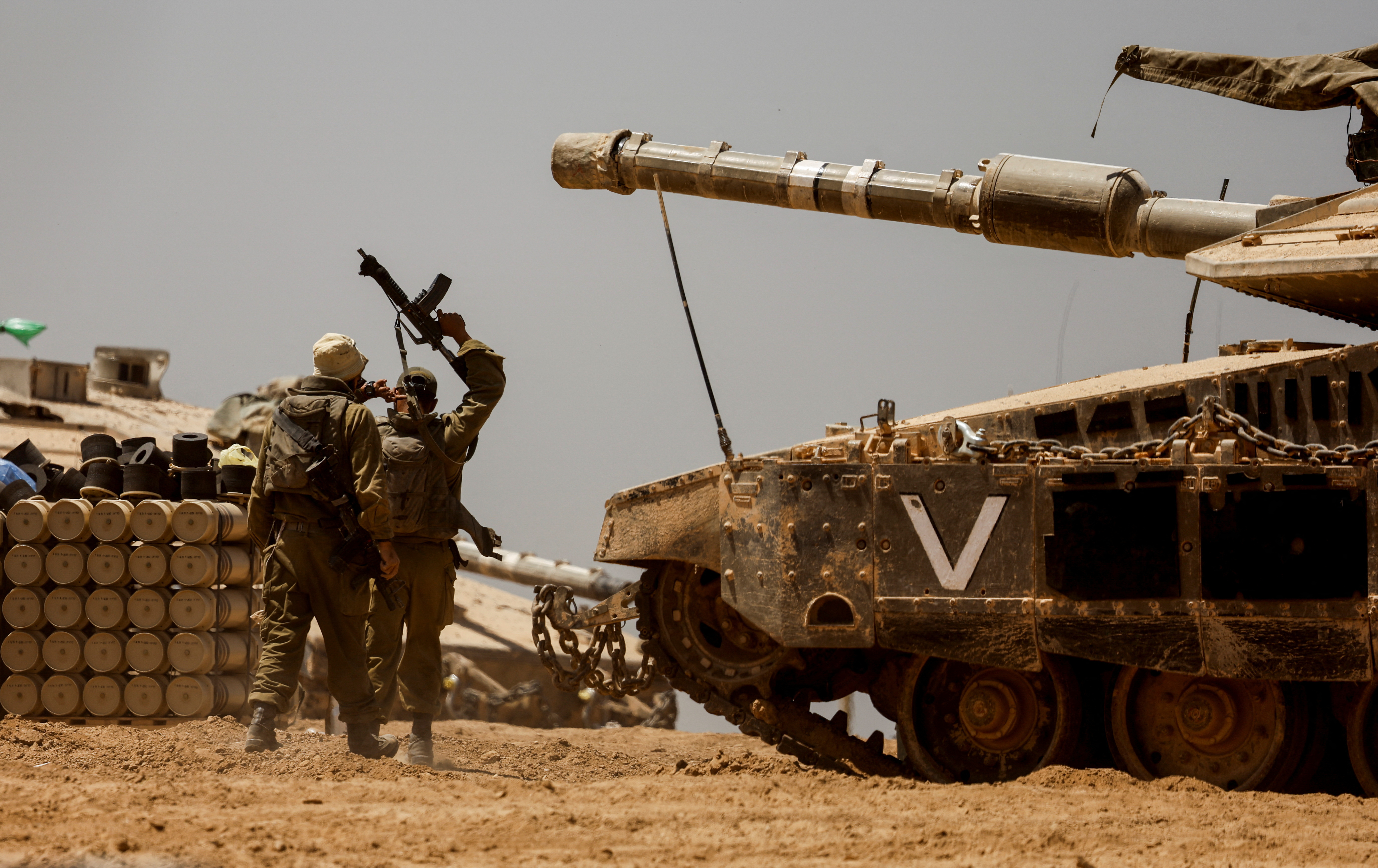 Israeli soldiers walk near a tank, near the Israel-Gaza Border, in southern Israel