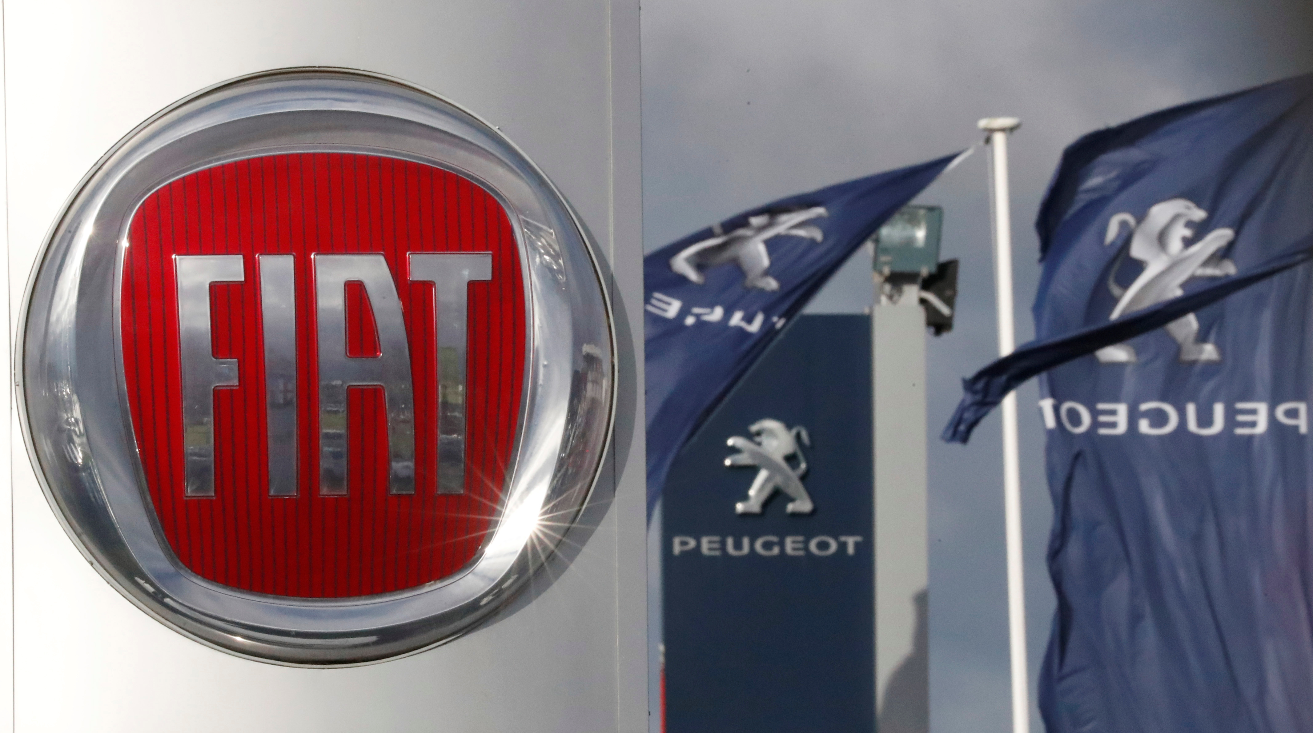The logos of car manufacturers Fiat and Peugeot are seen in front of dealerships of the companies in Saint-Nazaire
