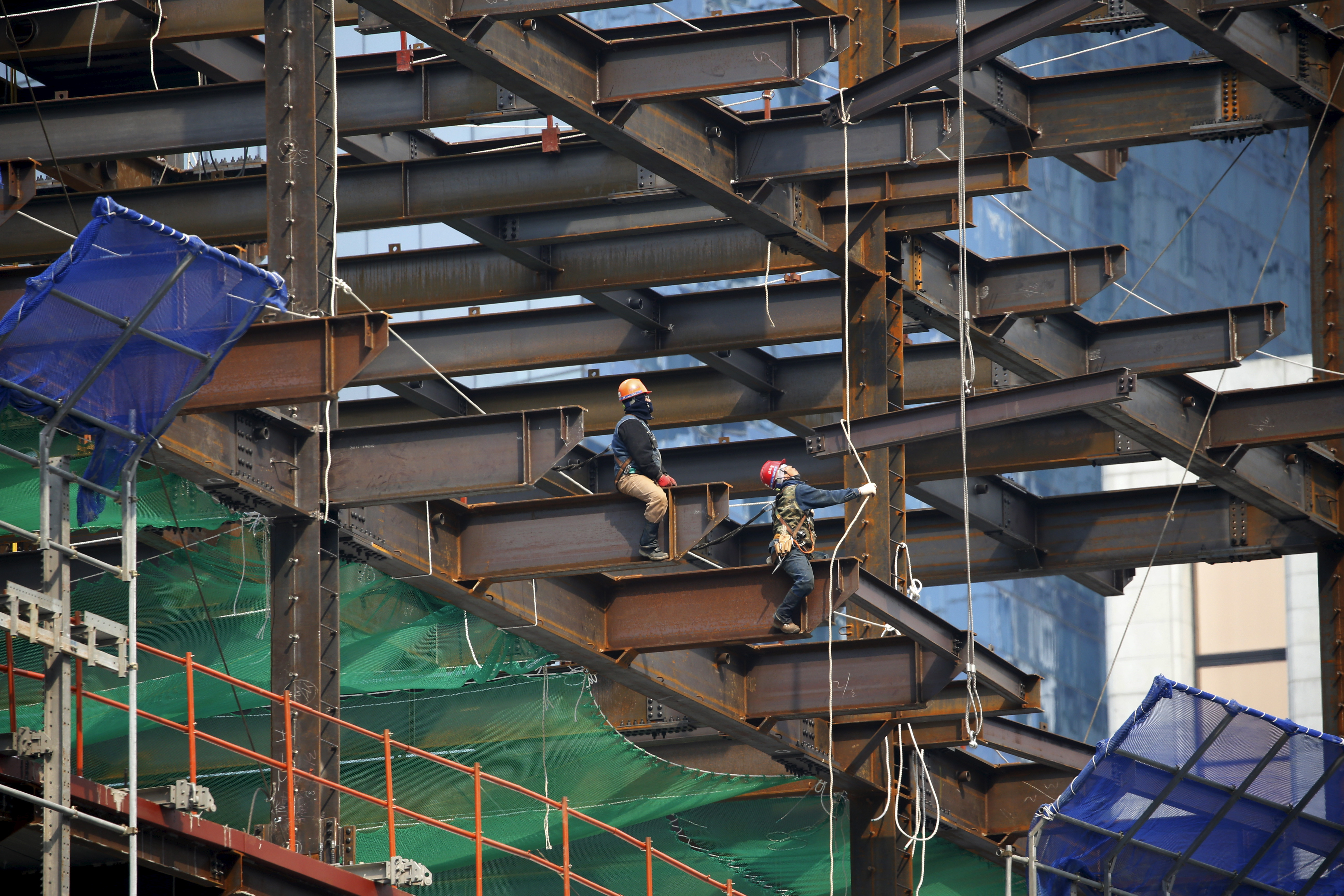 FILE PHOTO - Workers labour on a steel frame at a construction site in central Seoul