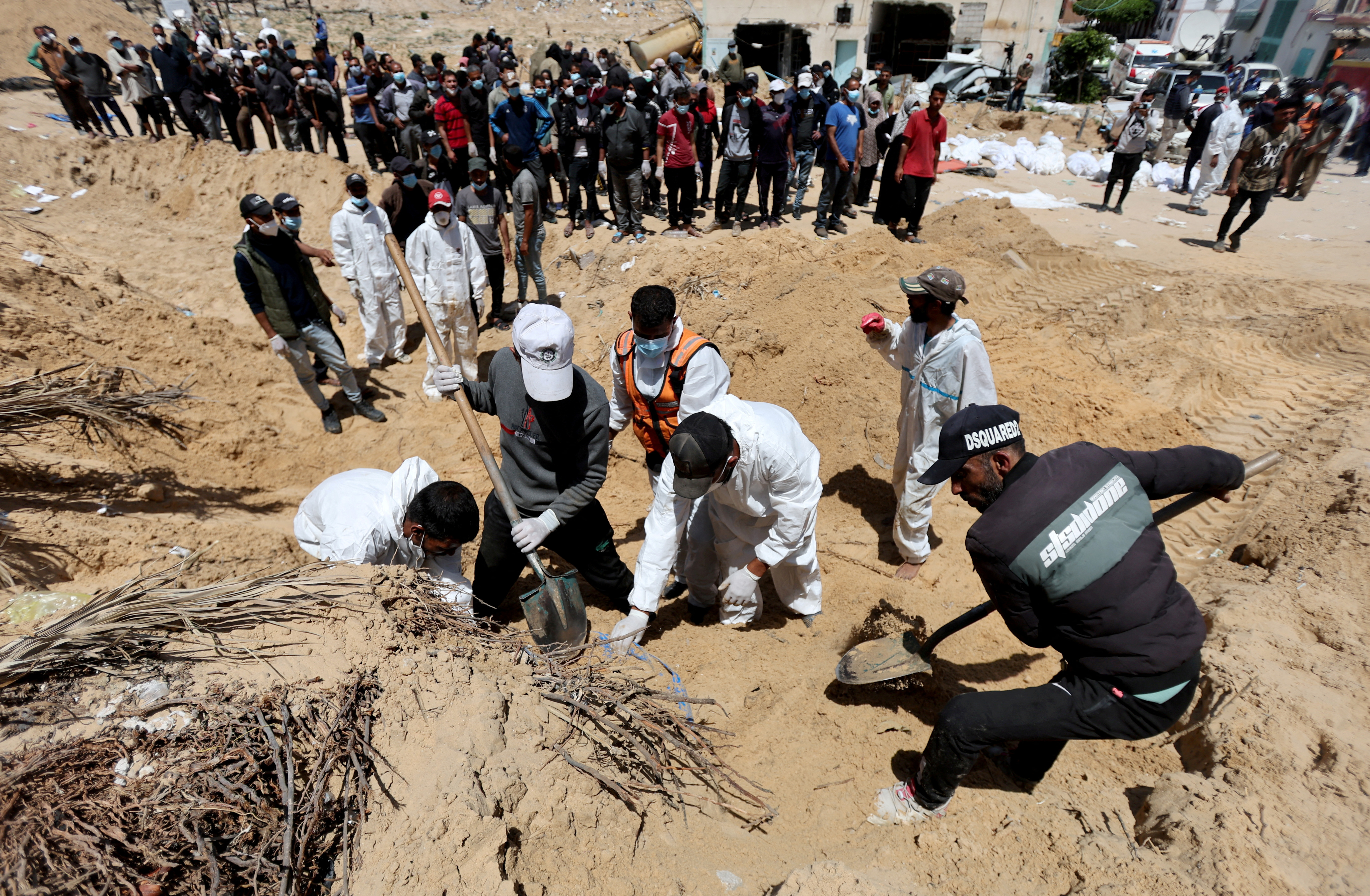 People work to move into a cemetery bodies of Palestinians killed during Israel's military offensive and buried at Nasser hospital, in Khan Younis