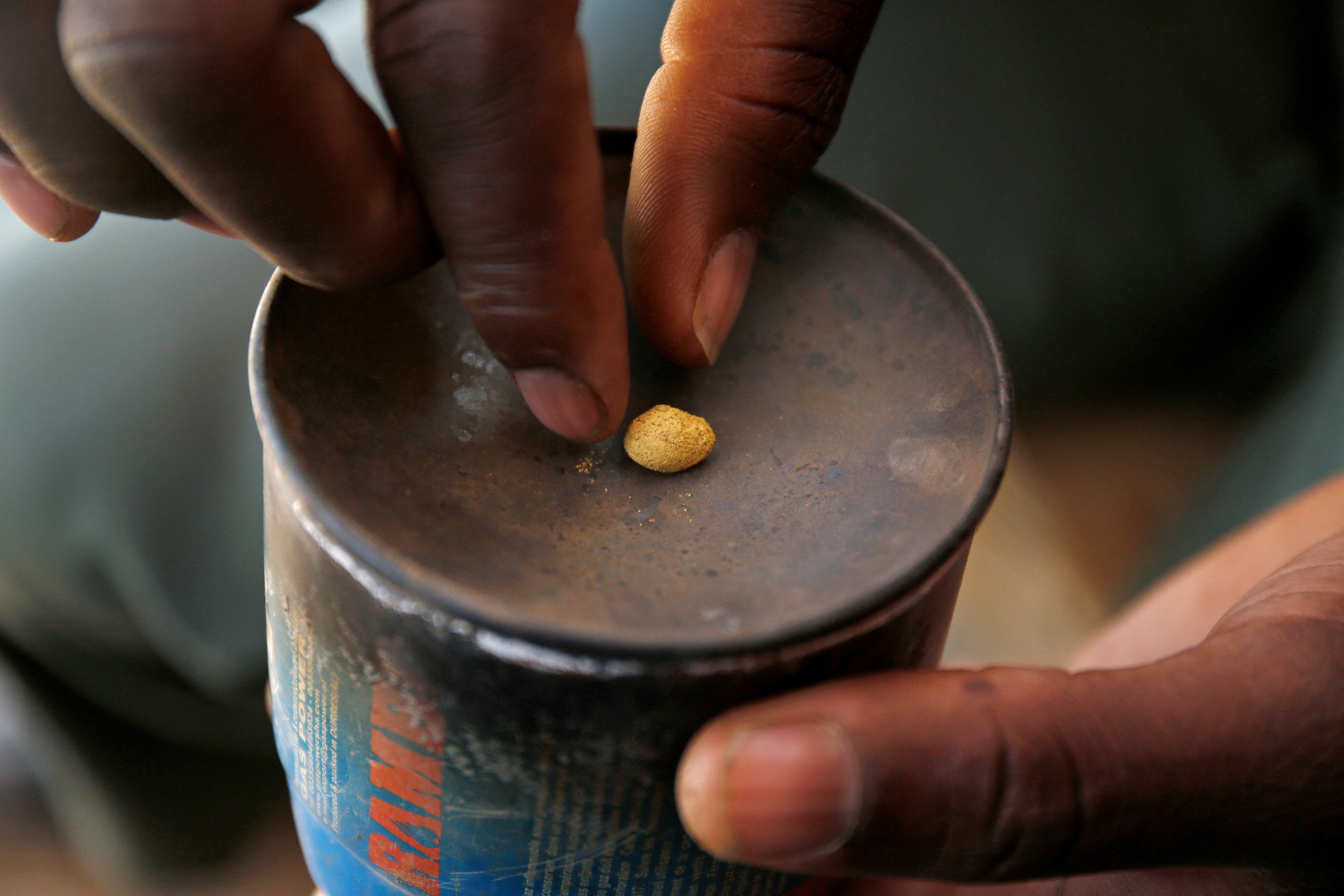 An artisanal gold miner picks up a gold nugget at an unlicensed mine in Gaoua, Burkina Faso