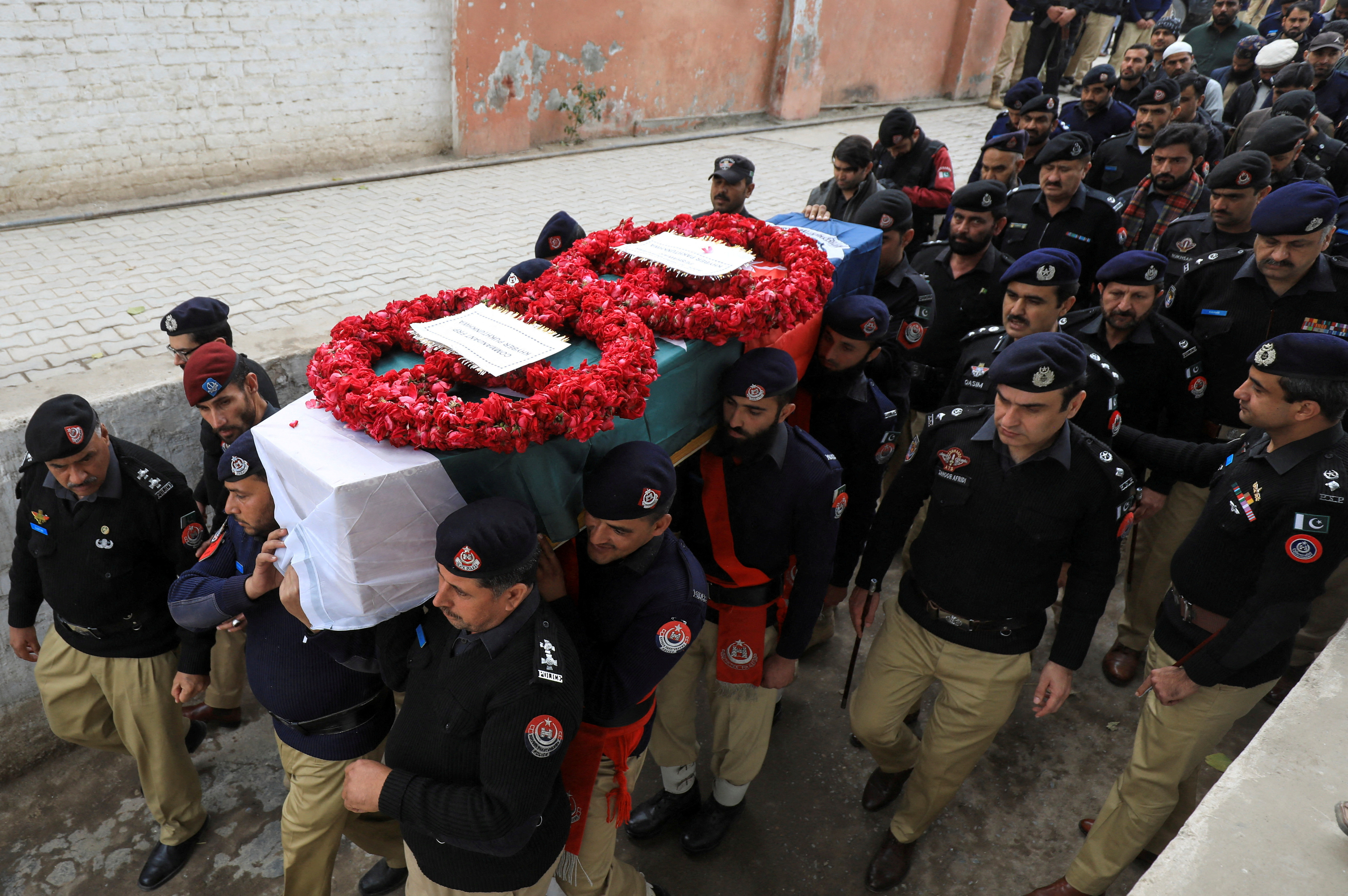 Police officers carry the coffin of Zeeshan, who along with others was killed in a suicide blast in a mosque, during his funeral in Peshawar
