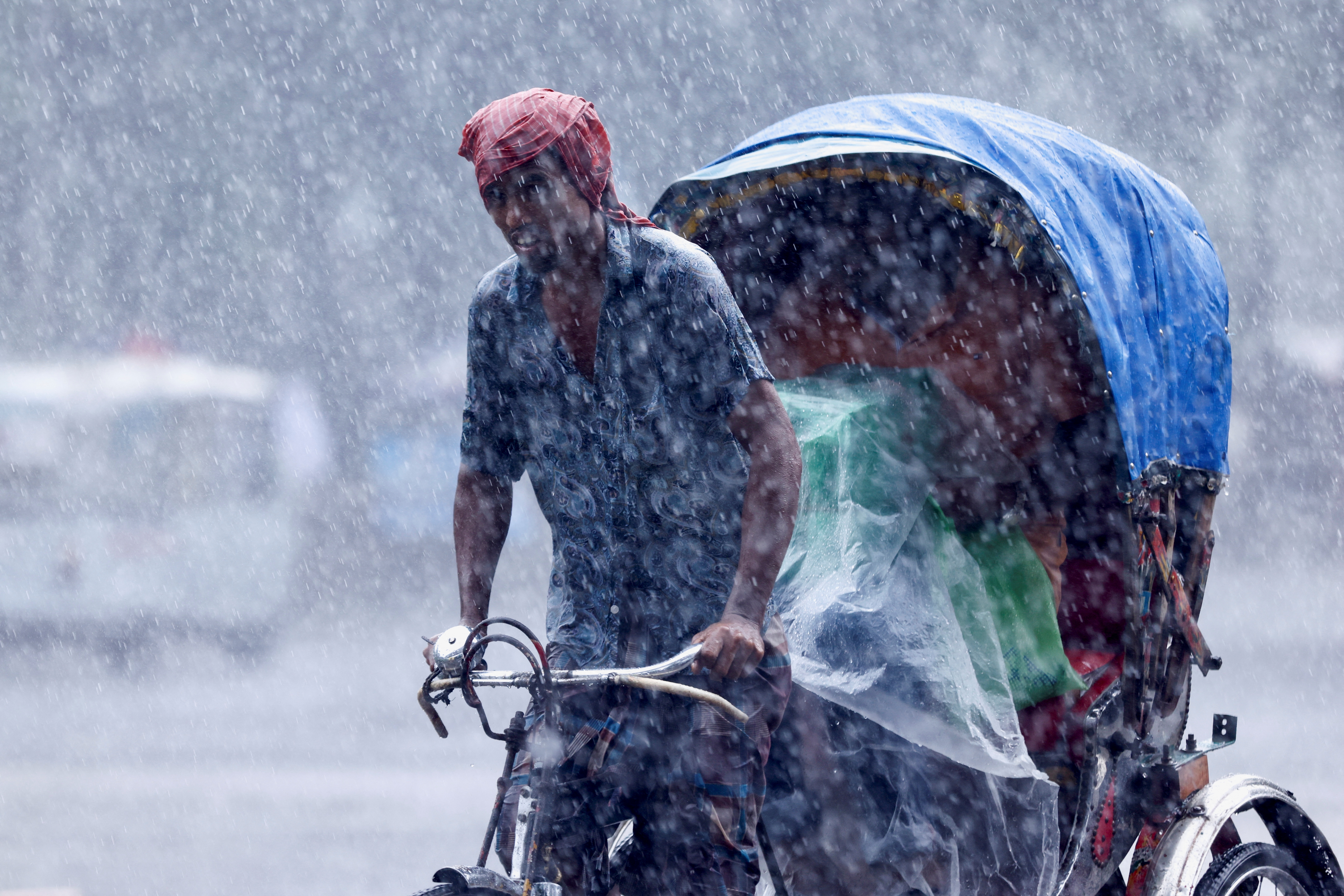 A man pulls a rickshaw during heavy rains in Dhaka