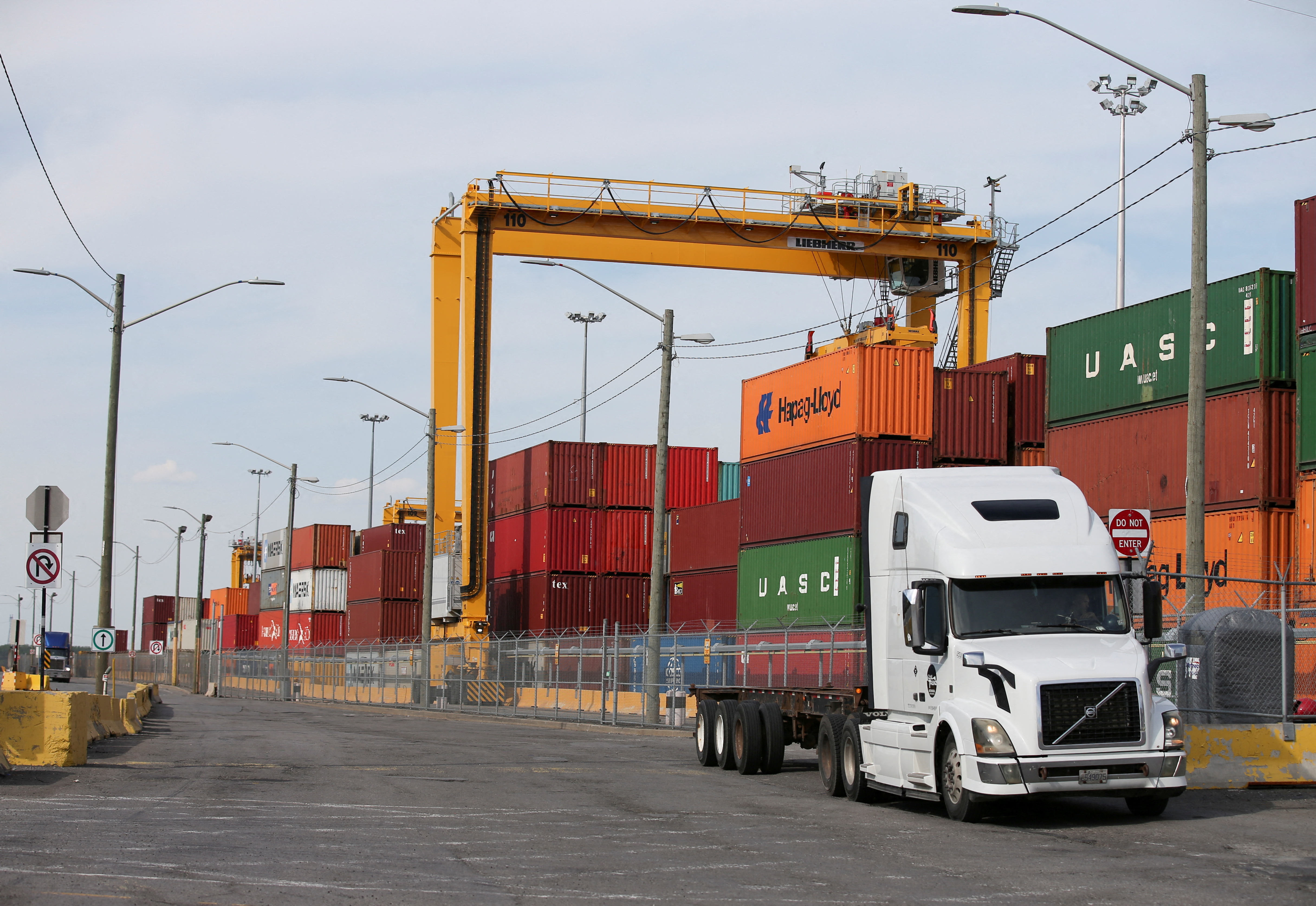 A truck moves past stacked shipping containers at the Port of Montreal