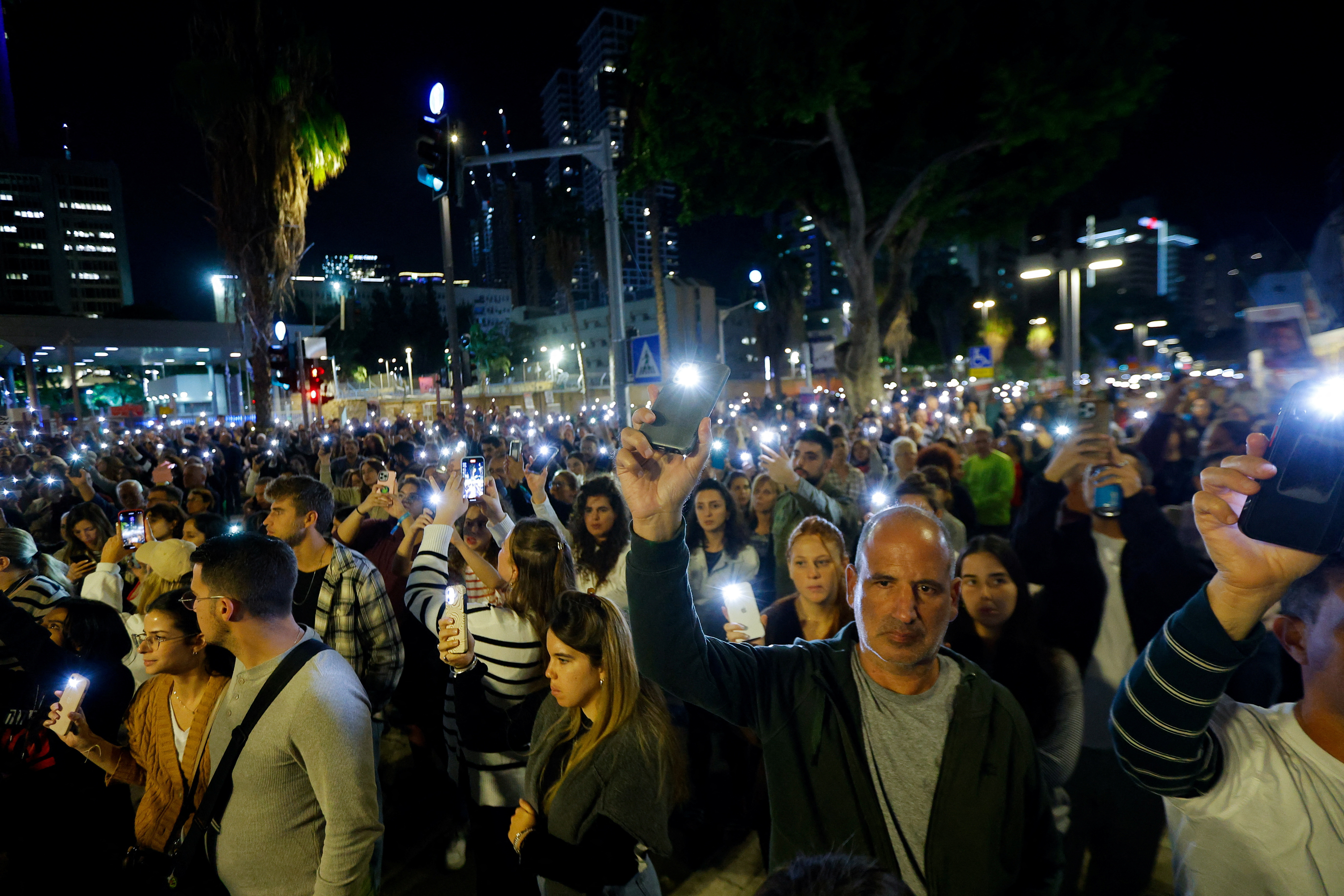 İnsanlar Tel Aviv'de Hamas'ın serbest bırakması beklenen rehinelerle ilgili haberleri beklerken toplanıyor