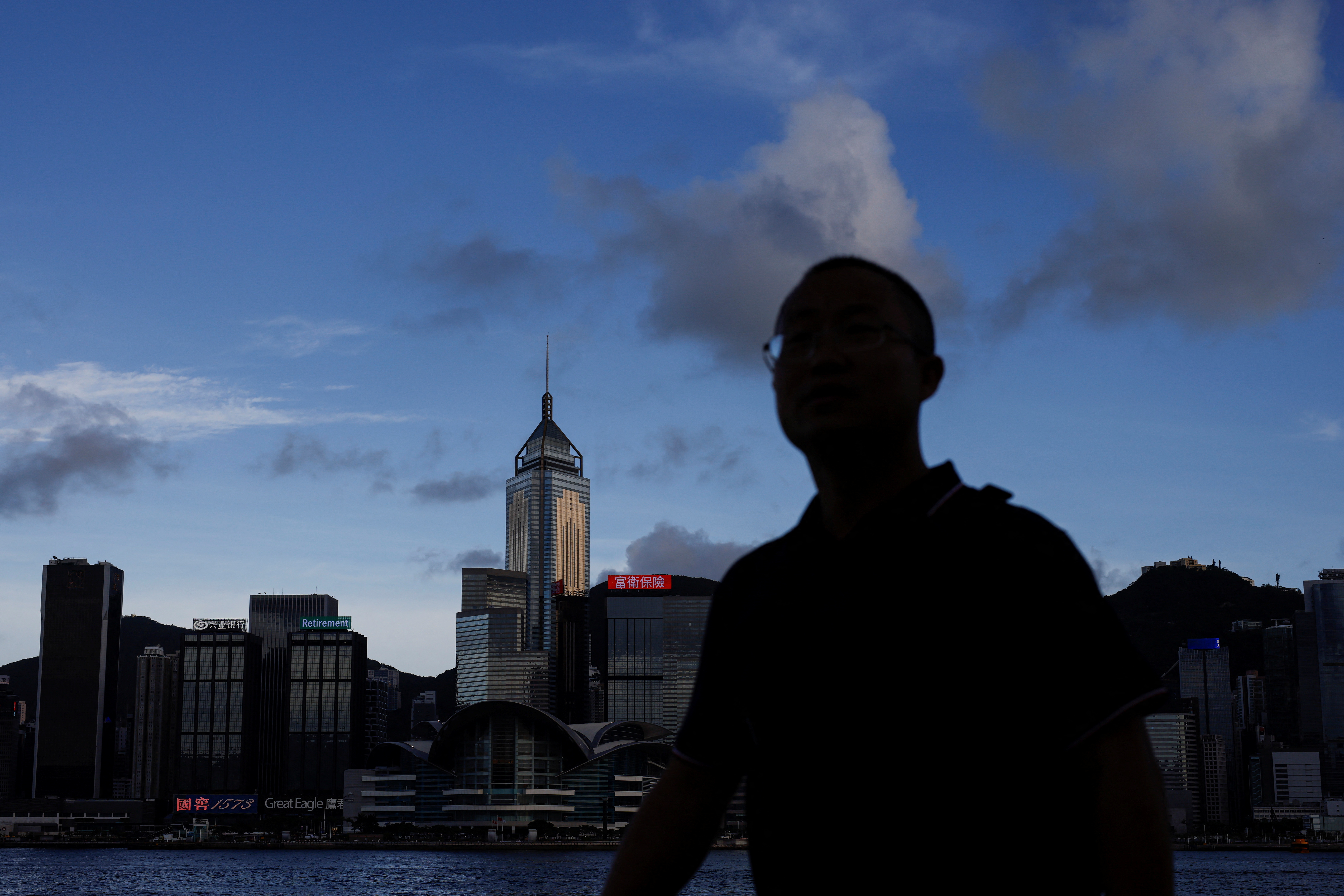 Man walks along the waterfront in front of Victoria Harbour, in Hong Kong