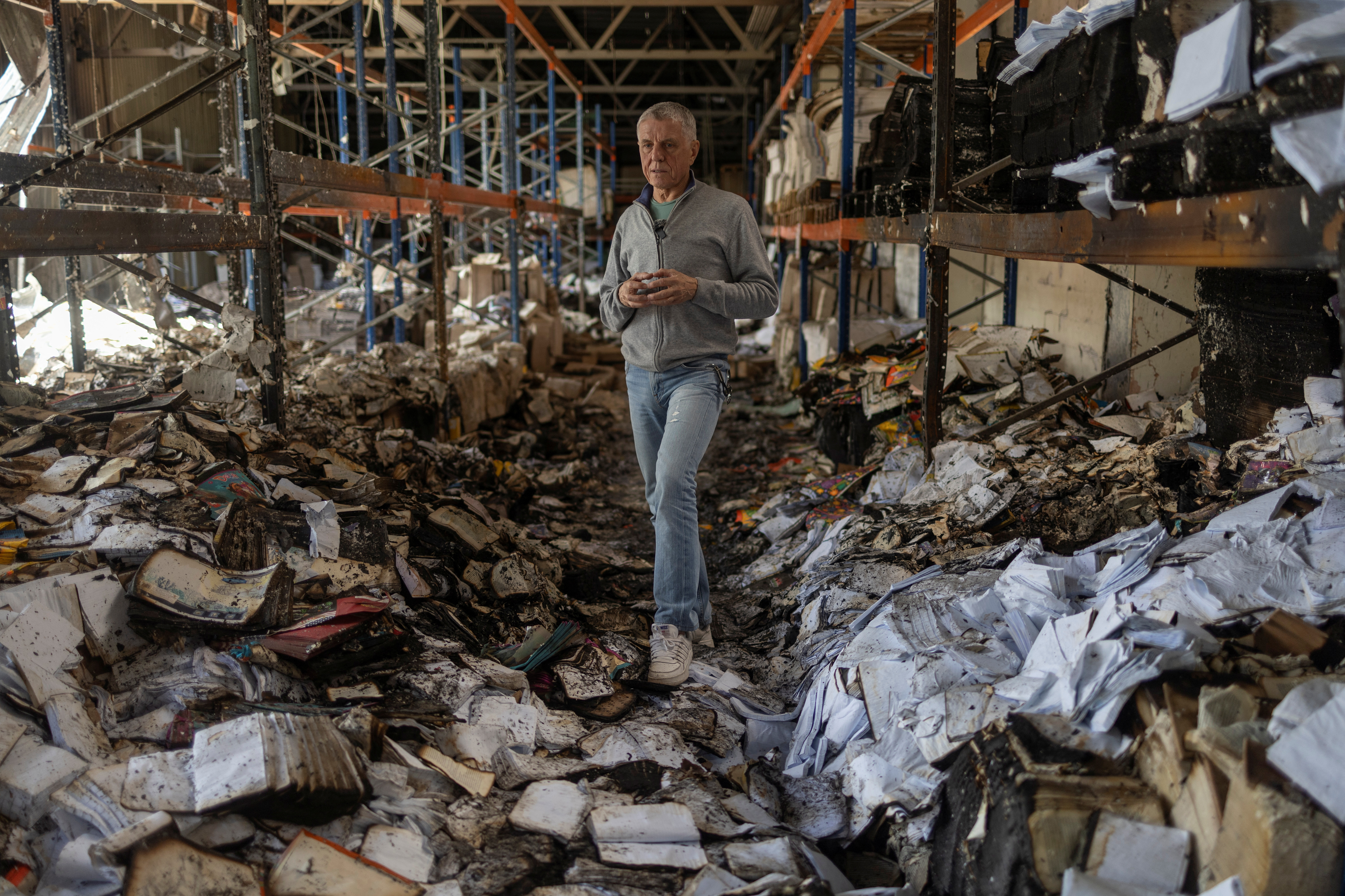 Sergii Polituchyi, Ukrainian publisher and businessman, stands between shelves with burned books in his printing house, which was badly damaged by a recent Russian missile strike, in Kharkiv