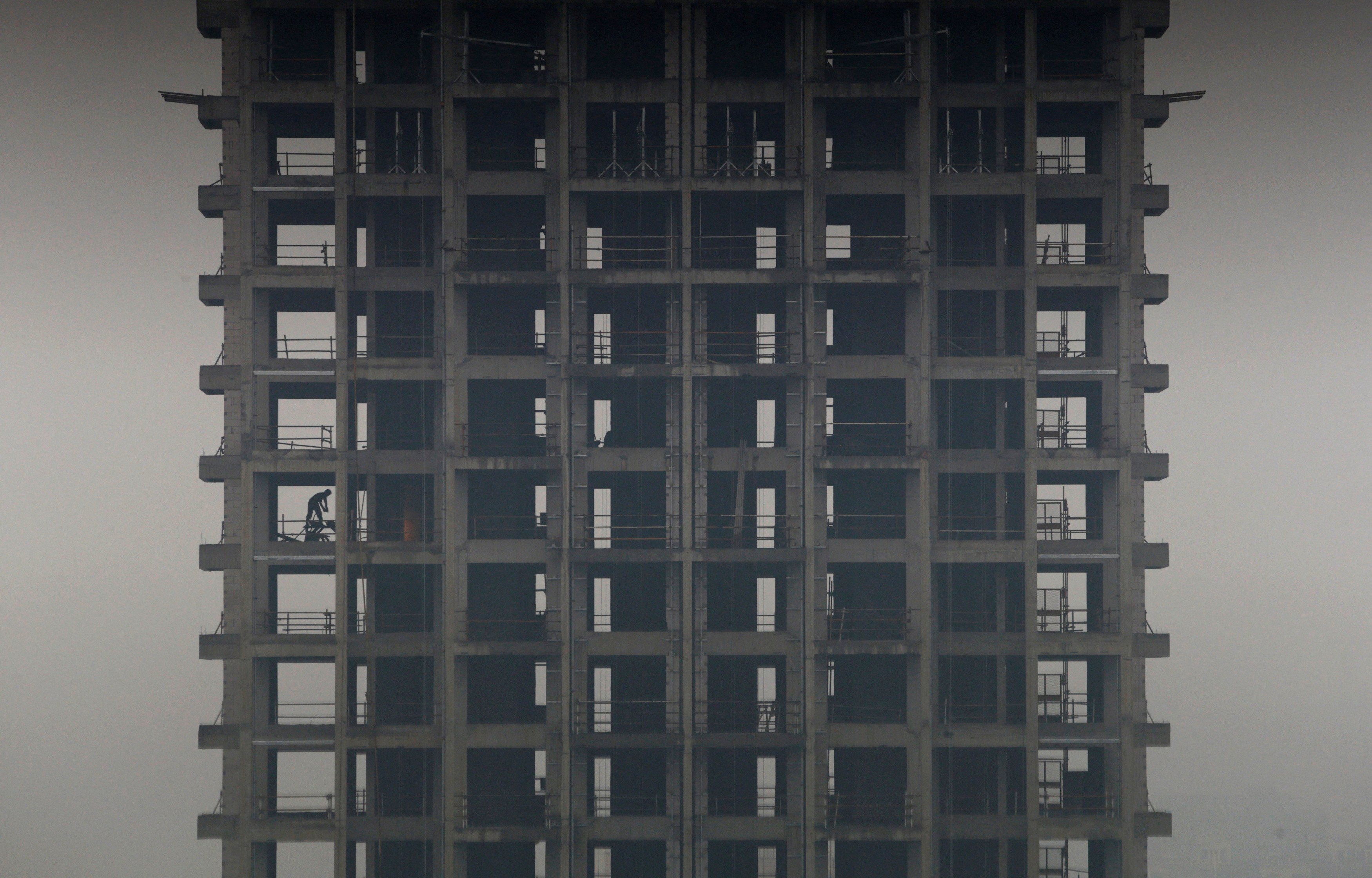 A labourer works on a construction site of a residential building during a hazy day in Hangzhou