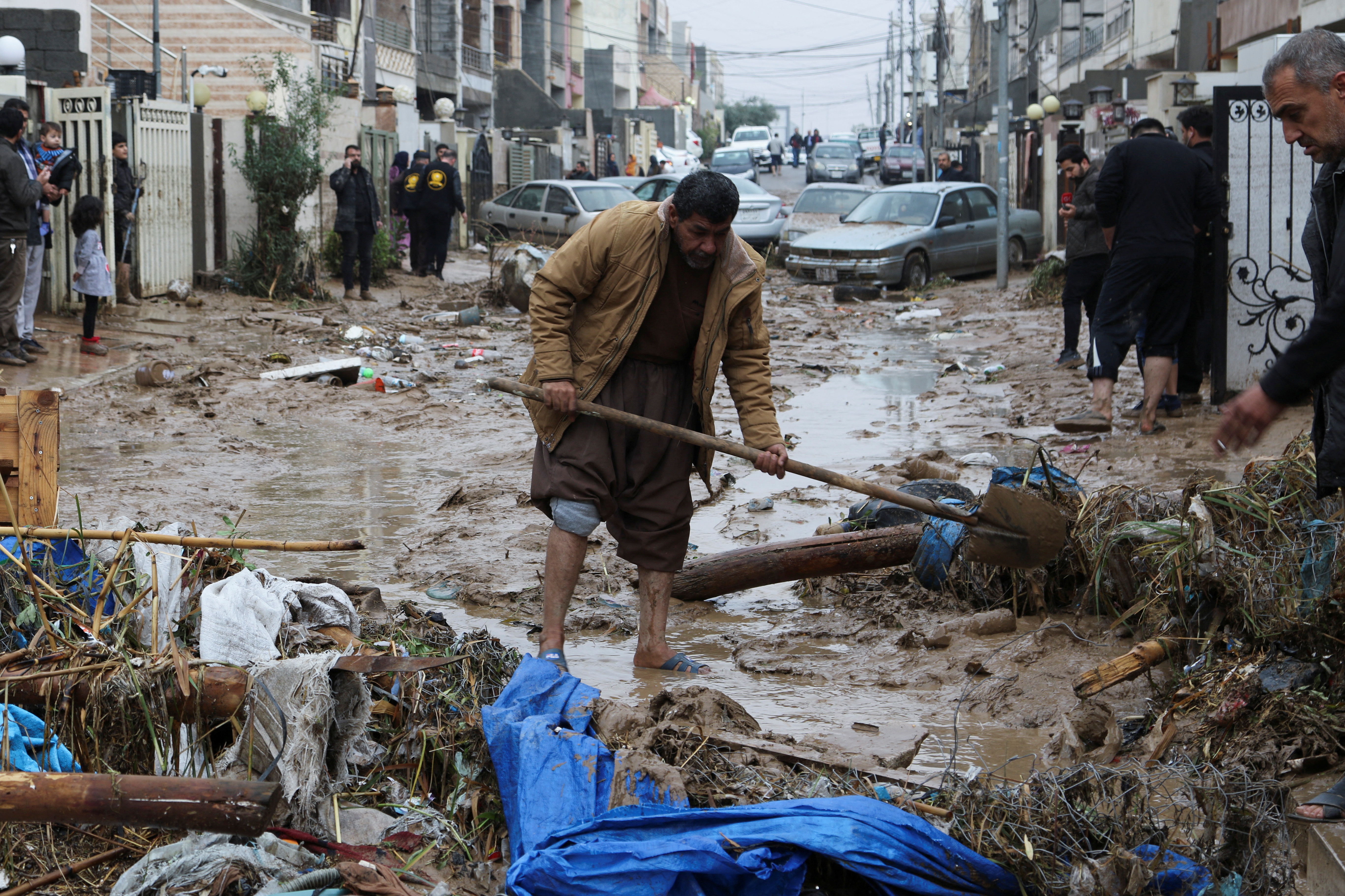 Residents clean a road full of mud after heavy rainfall in Erbil