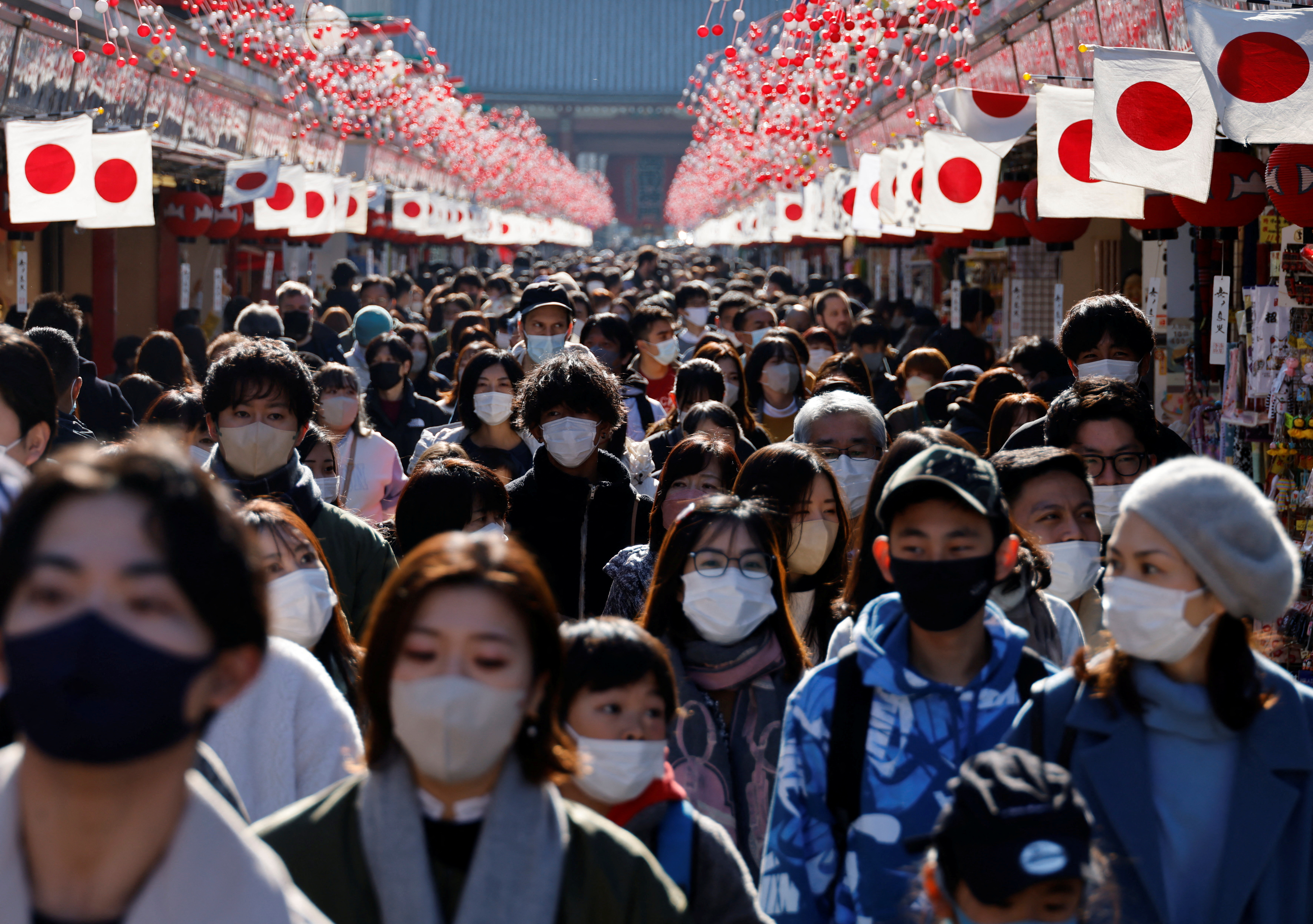 Visitors wearing protective face masks walk under decorations for the New Year at Asakusa district in Tokyo
