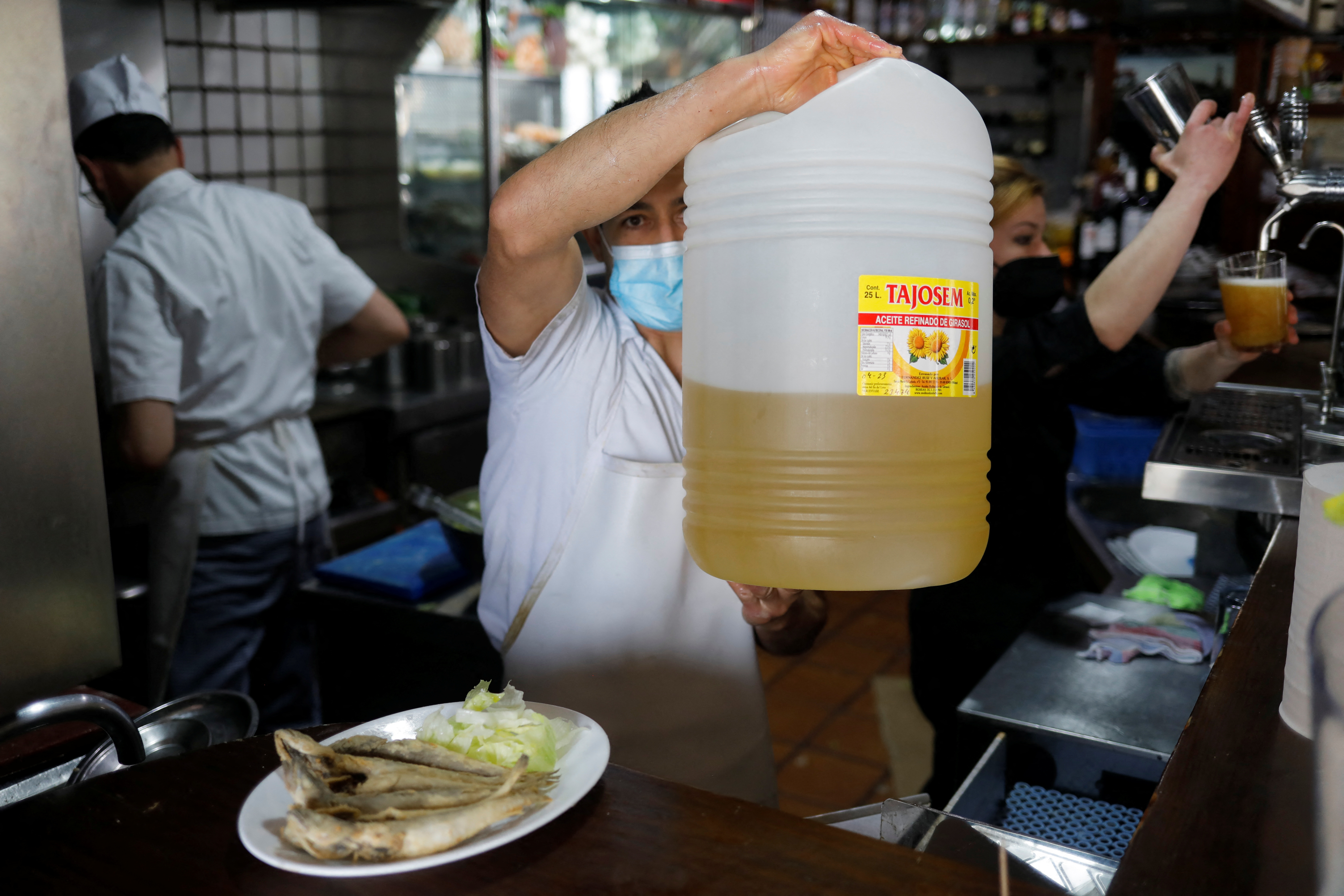 Waiter holds a plastic bottle with sunflower oil used to fry fish at Los Cazadores bar in Ronda