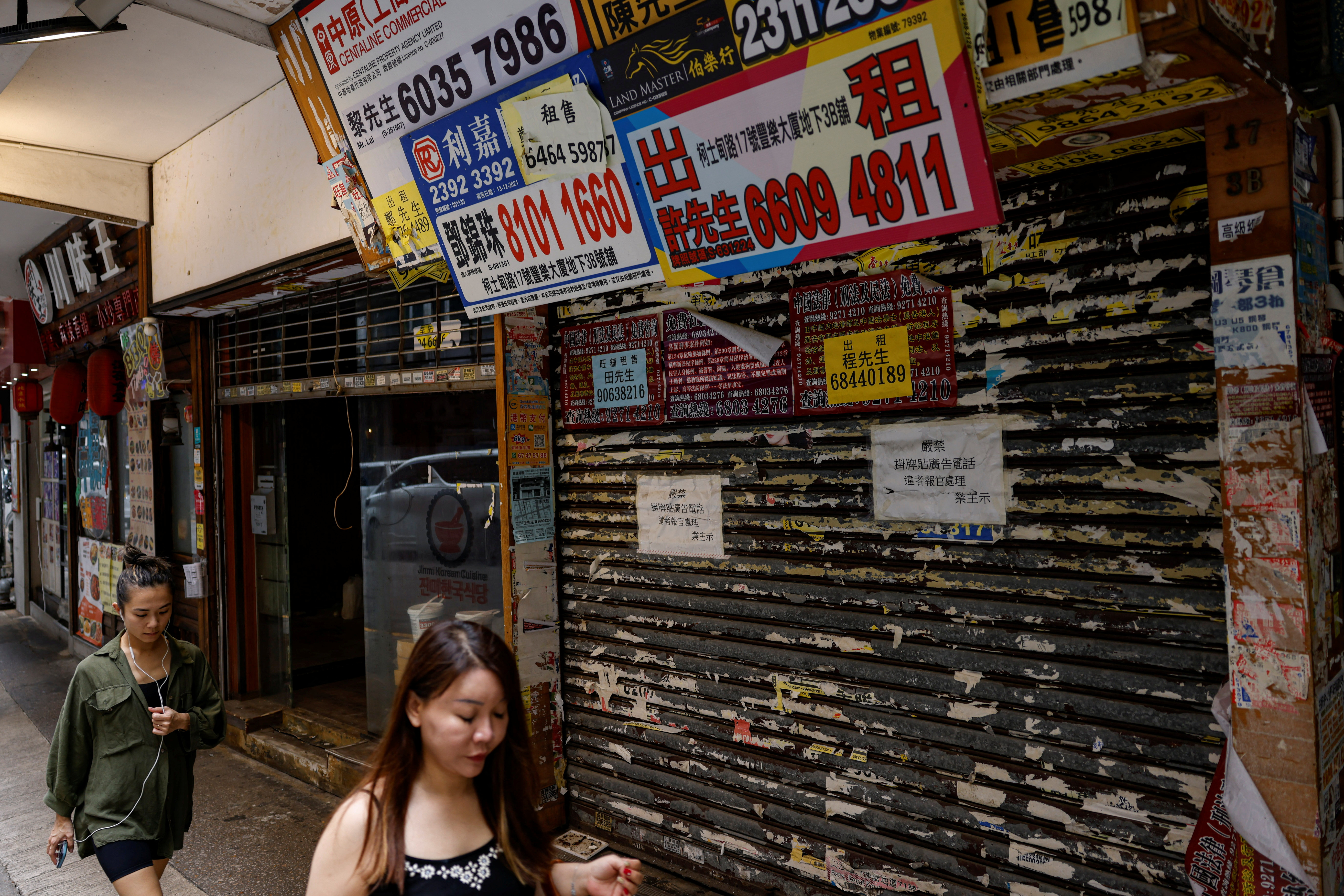People walk past a closed-down retail shop in Tsim Sha Tsui, Hong Kong