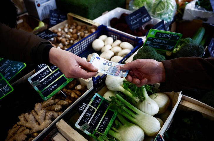 A shopper pays with a twenty Euro bank note at a local market in Nantes