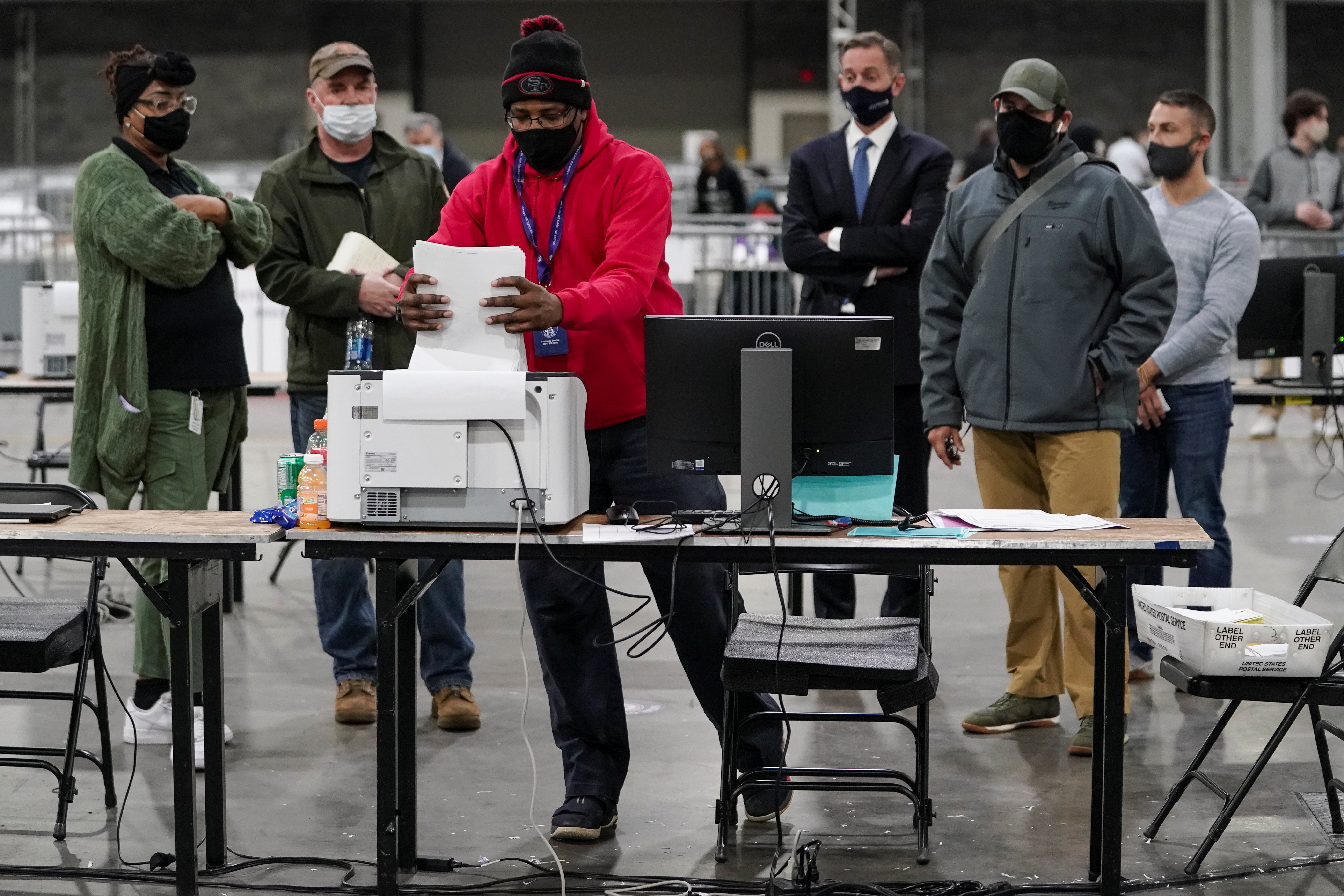 A Fulton County election worker puts absentee ballots in a scanner as election observers look on, at the Georgia World Congress Center in Atlanta, Georgia, U.S., January 5, 2021.  REUTERS/Elijah Nouvelage