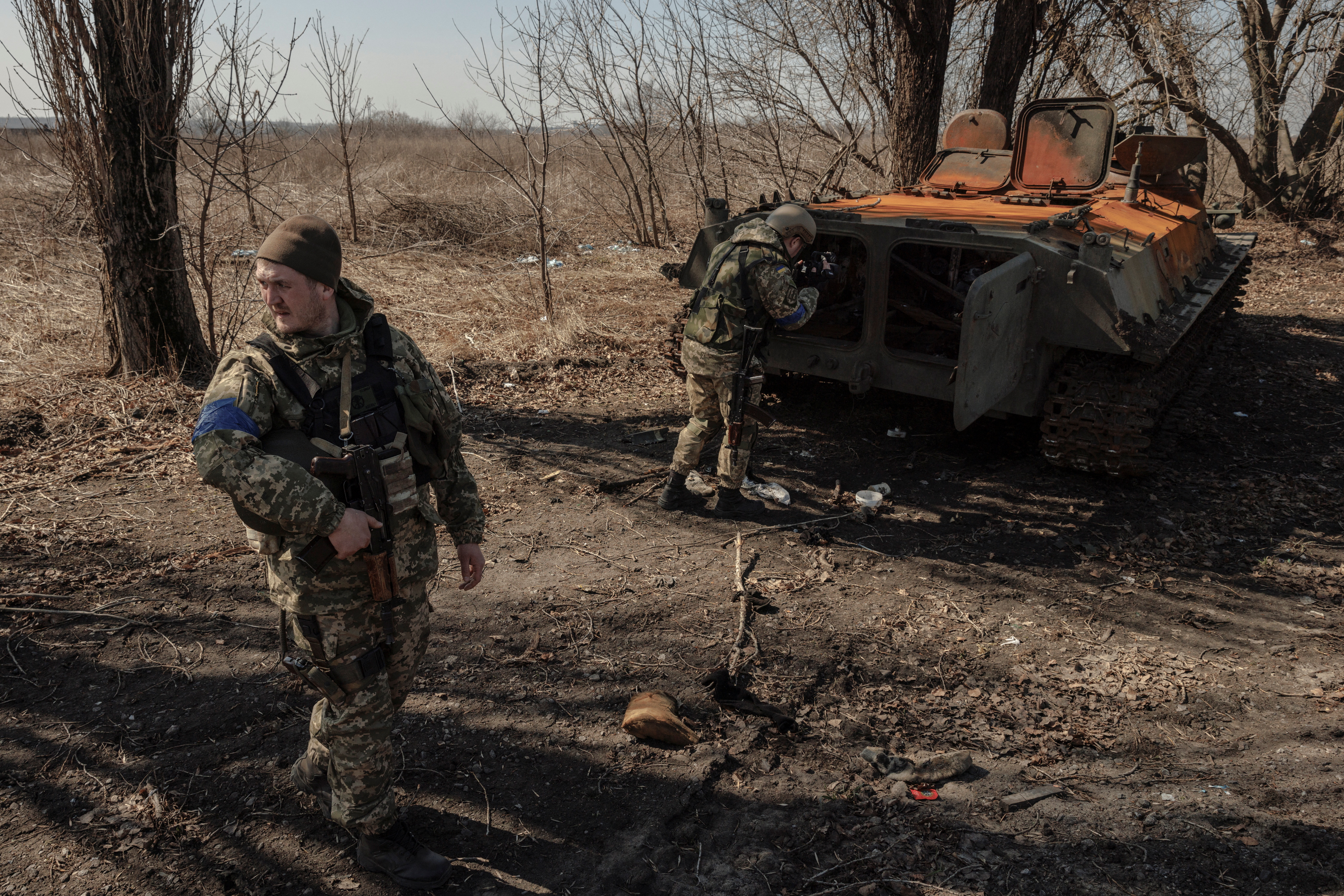 Ukrainian soldiers stand near a wrecked Russian armoured vehicle after a battle between Ukrainian and Russian troops outside Kharkiv