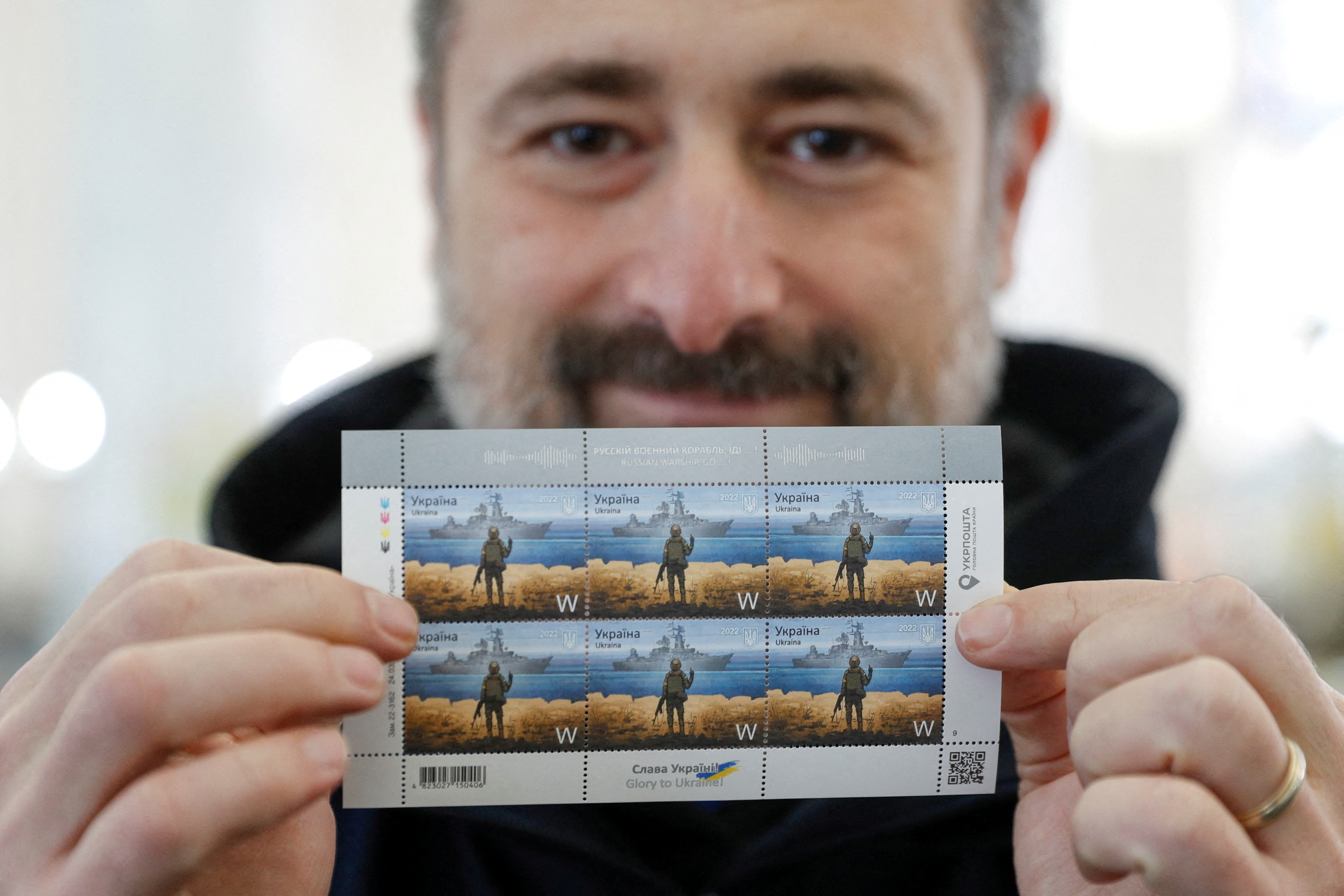 CEO of the Ukrainian post Smilianskyi demonstrates postal stamps showing Ukrainian service member and Russian warship, at company's headquarters in Kyiv
