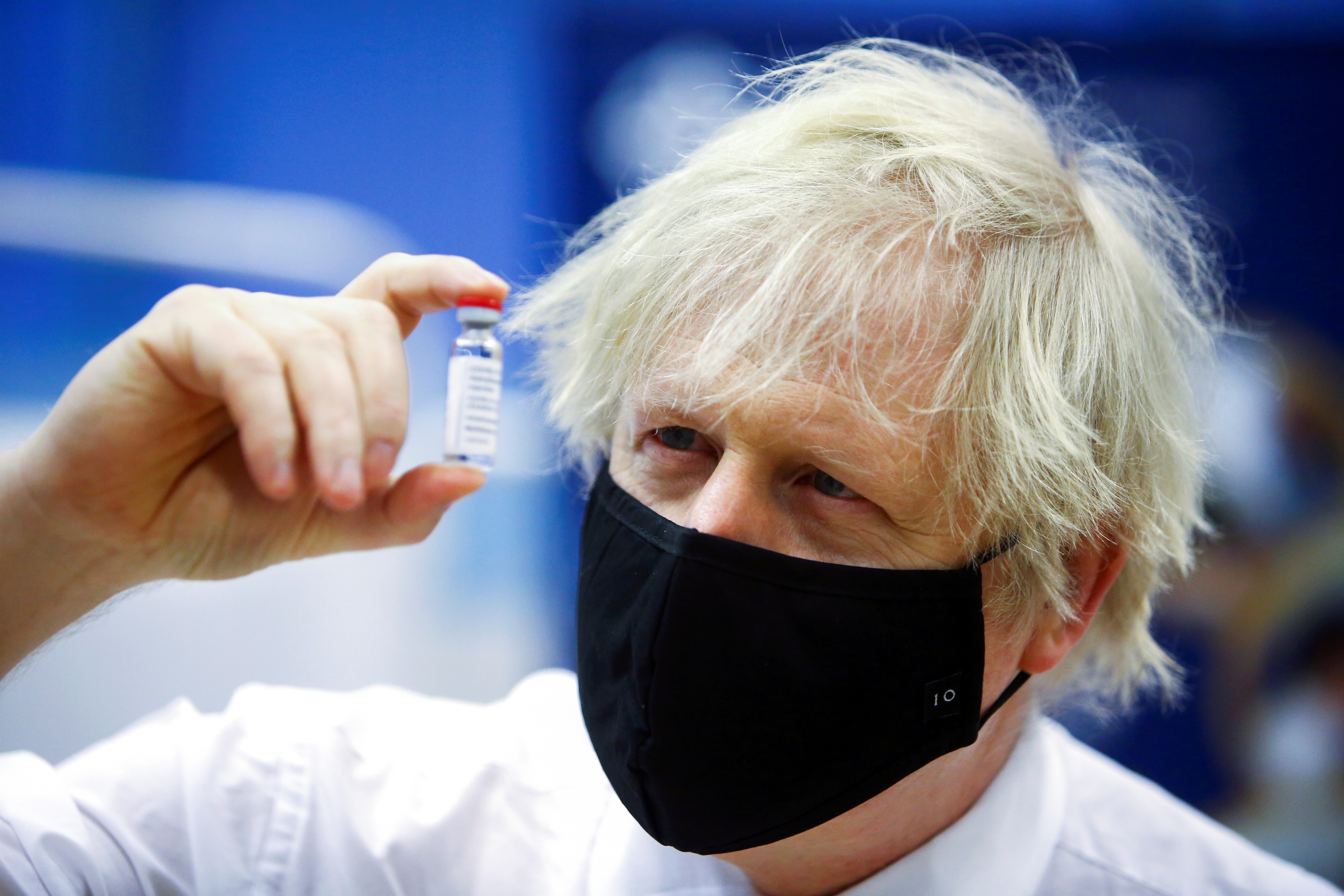 Britain's Prime Minister Boris Johnson holds a vial of an Oxford-AstraZeneca COVID-19 vaccine, during his visit at a vaccination centre at Cwmbran Stadium in Cwmbran, south Wales, Britain February 17, 2021. Geoff Caddick/Pool via REUTERS