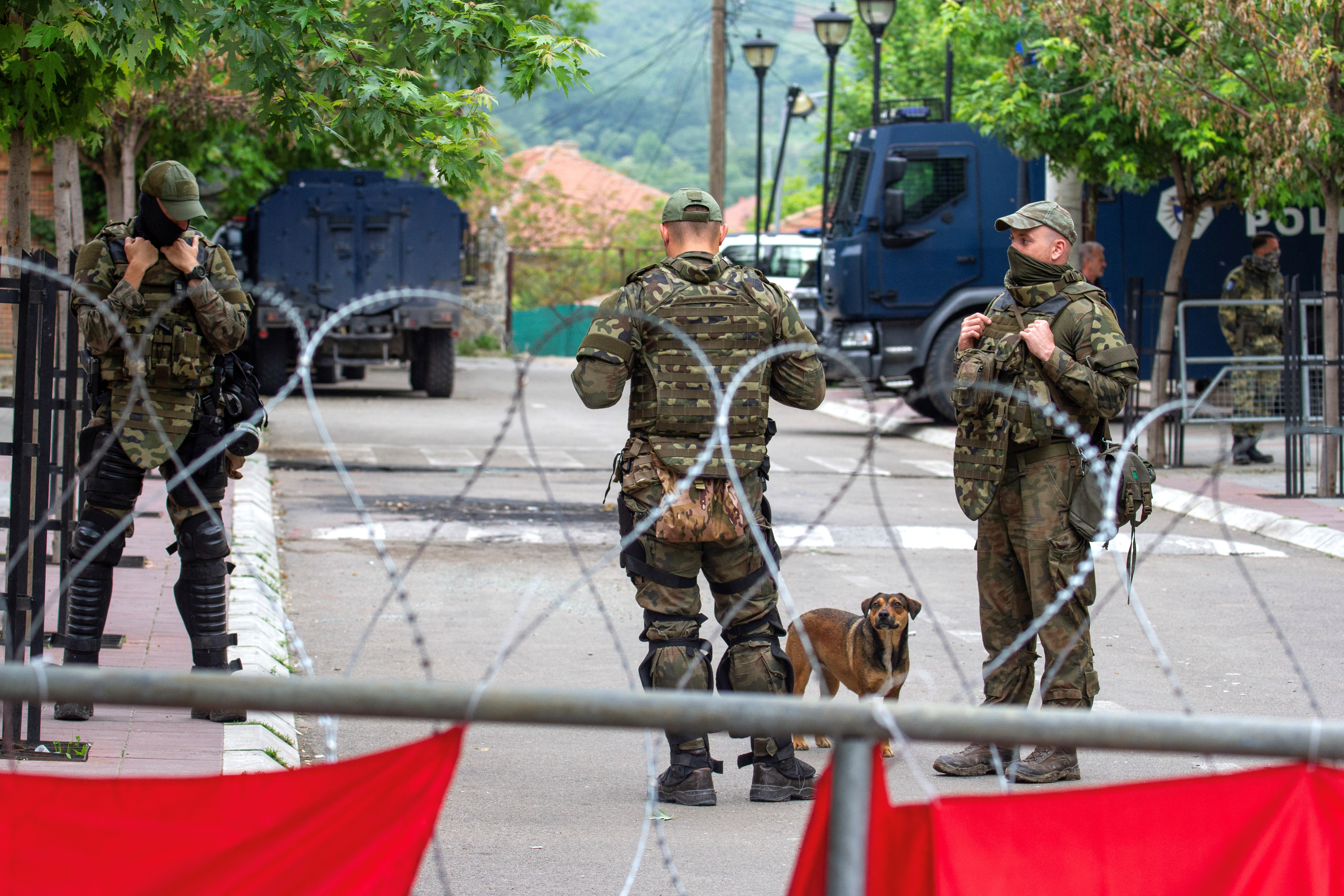 NATO Kosovo Force (KFOR) soldiers stand guard behind razor wire fence in the town of Zvecan