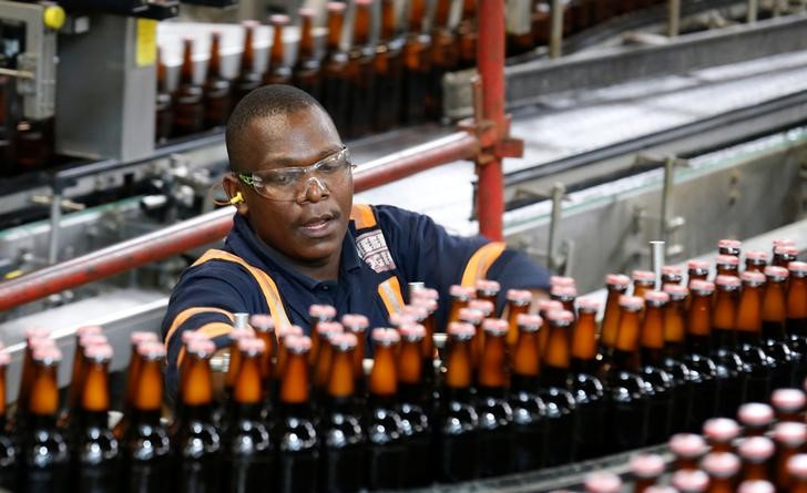An employee inspects bottles of beer on a conveyor belt at the production line inside the East African Breweries Limited factory in Ruaraka factory in Nairobi