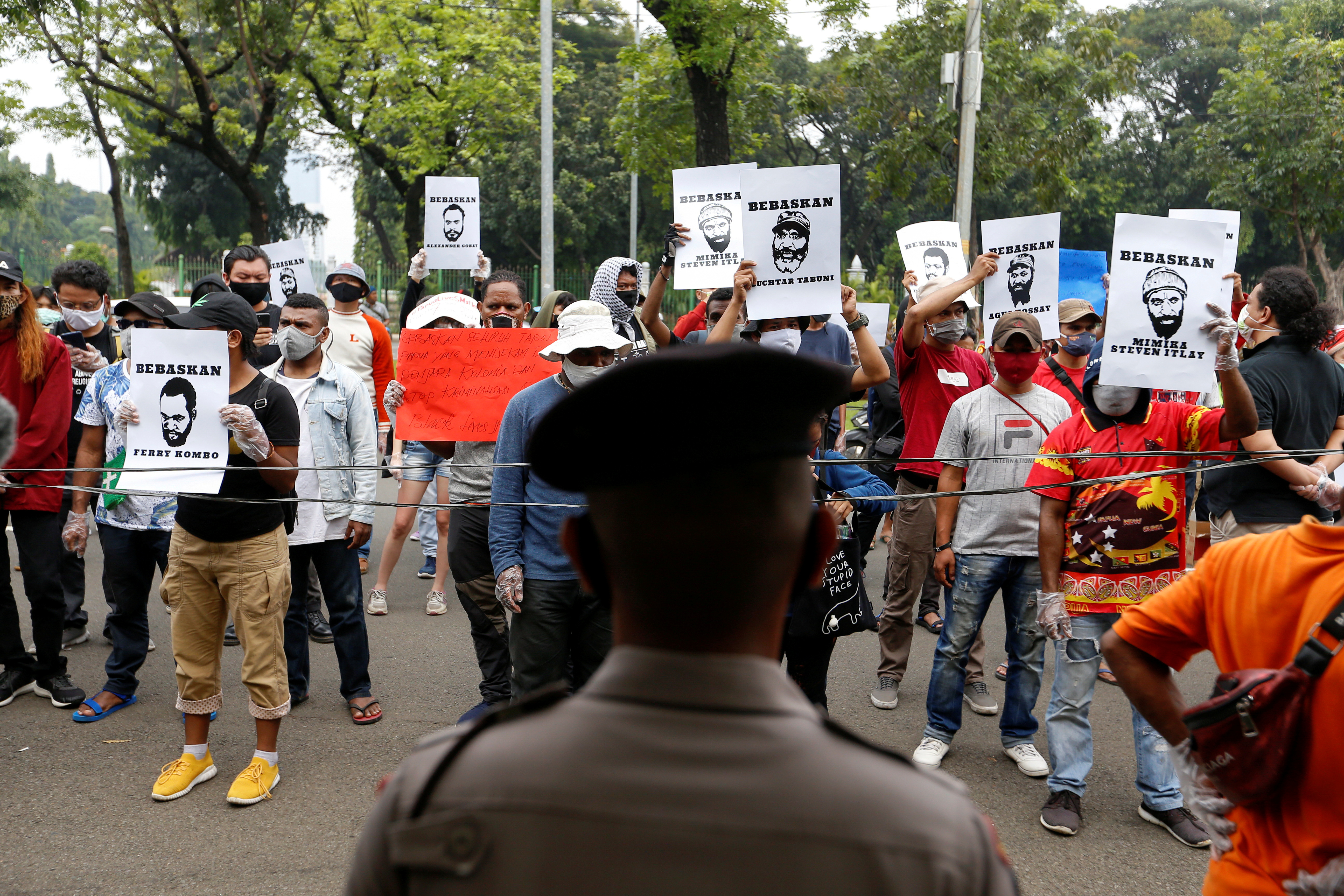 Demonstrators hold signs during a protest in front of the Supreme Court building in Jakarta