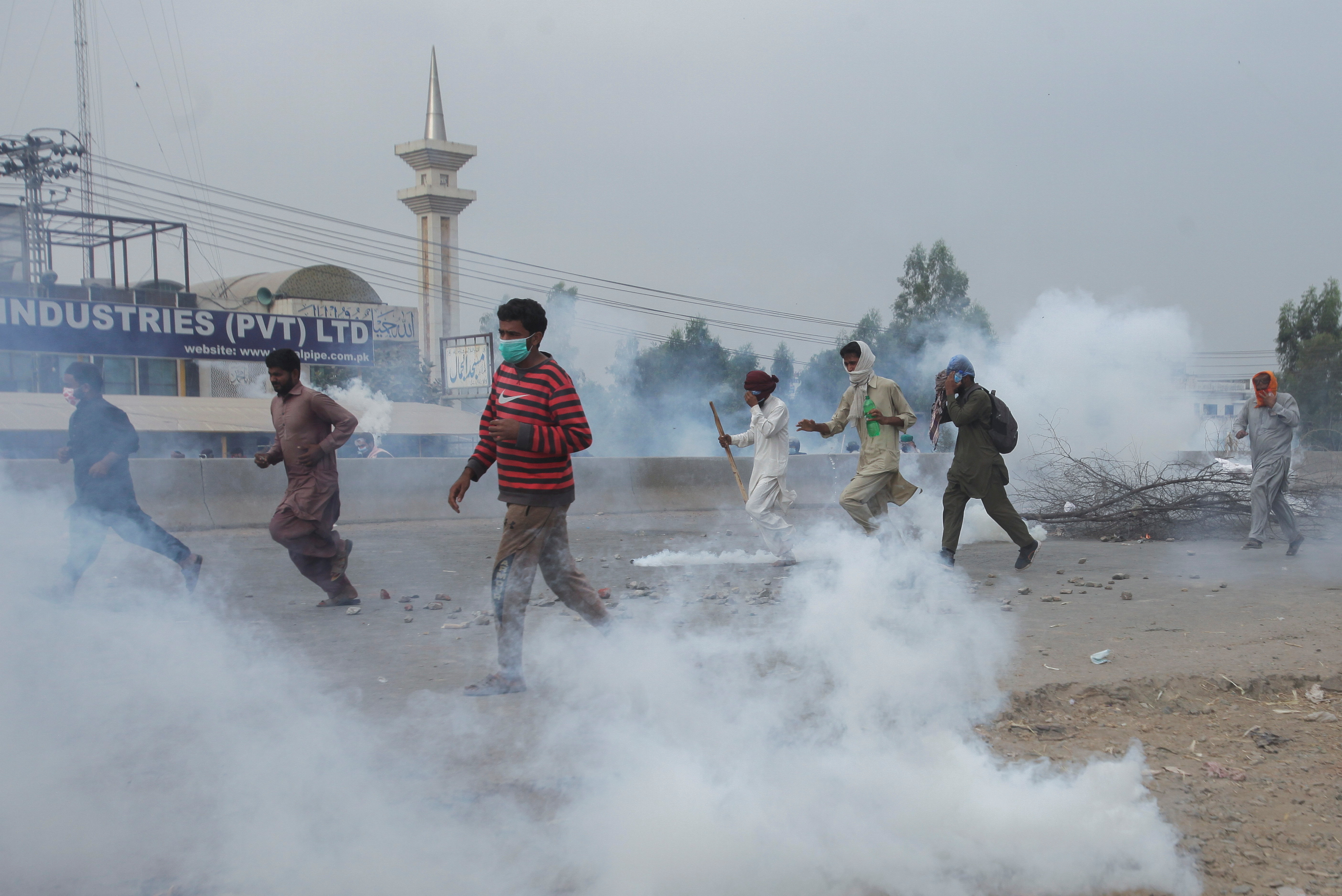 Supporters of the banned Islamist political party Tehrik-e-Labaik Pakistan (TLP) run amid the smoke of tear gas during a protest demanding the release of their leader and the expulsion of the French ambassador over cartoons depicting the Prophet Mohammad, in Lahore, Pakistan, October 23, 2021. REUTERS/Mohsin Raza/File Photo