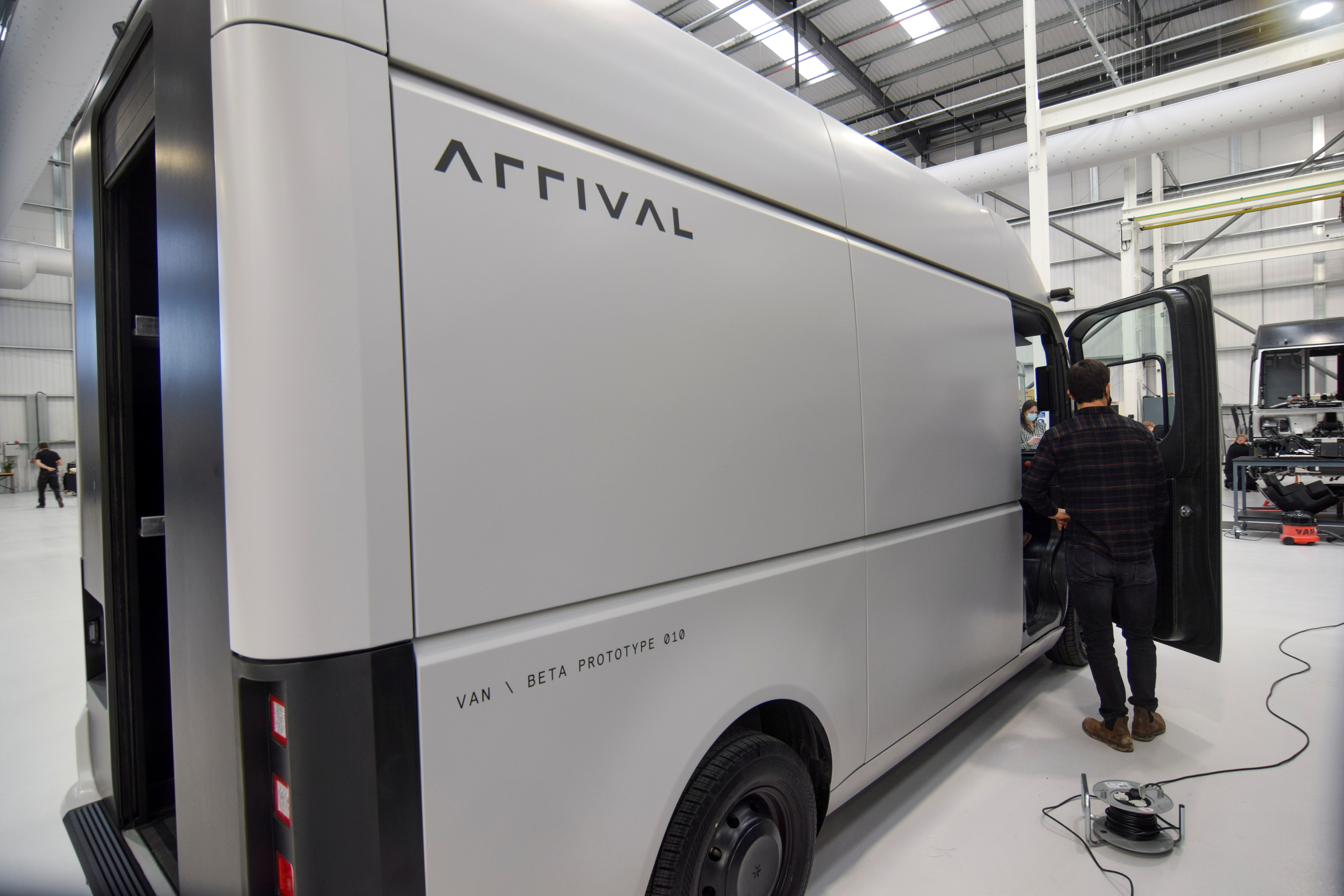 A man stands next to a fully-electric test van, due to go into production in 2022, in Banbury