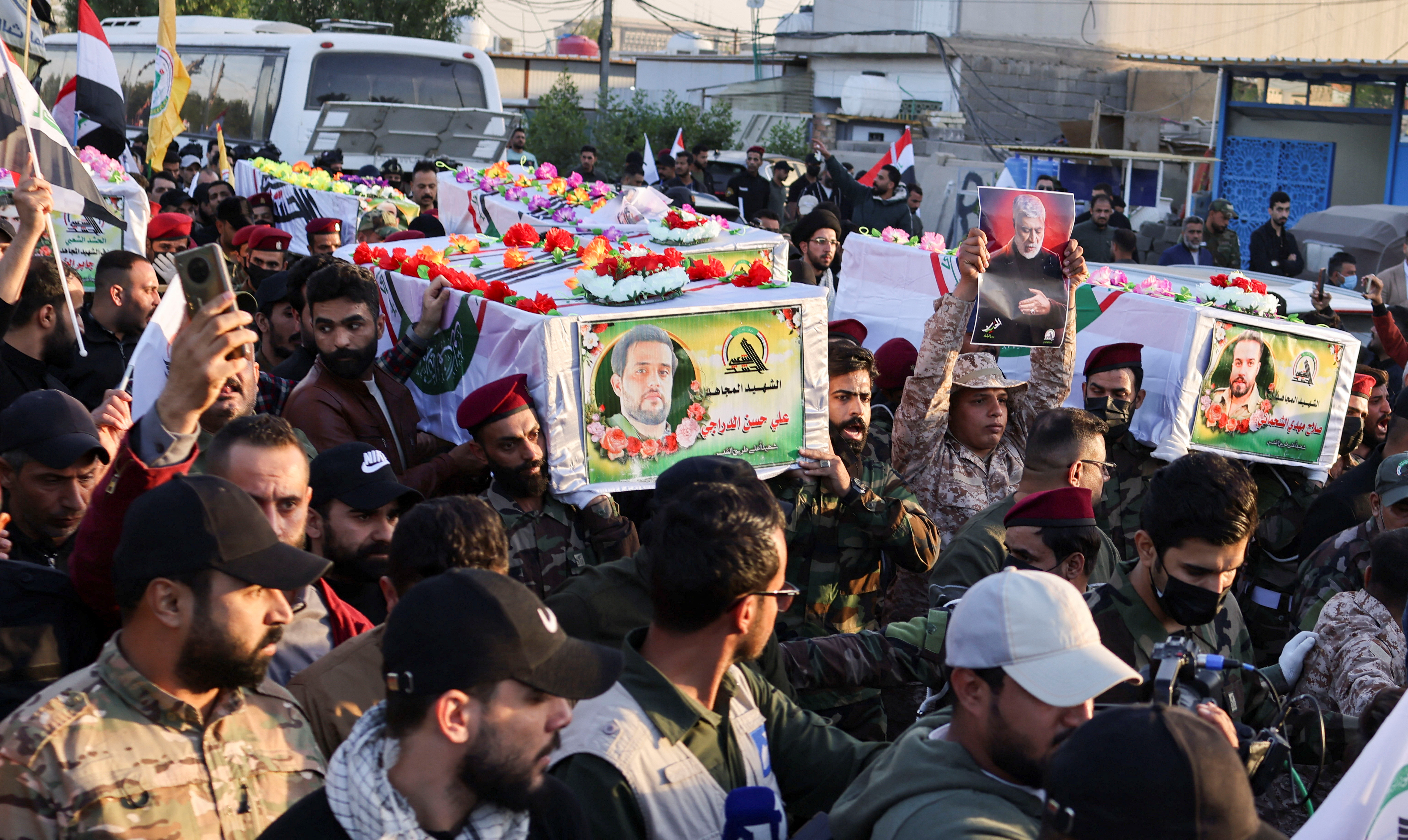 Mourners carry the coffins of Iraq's Kataib Hezbollah fighters who were killed by US airstrike in Jurf al-Sakhar, south of Baghdad