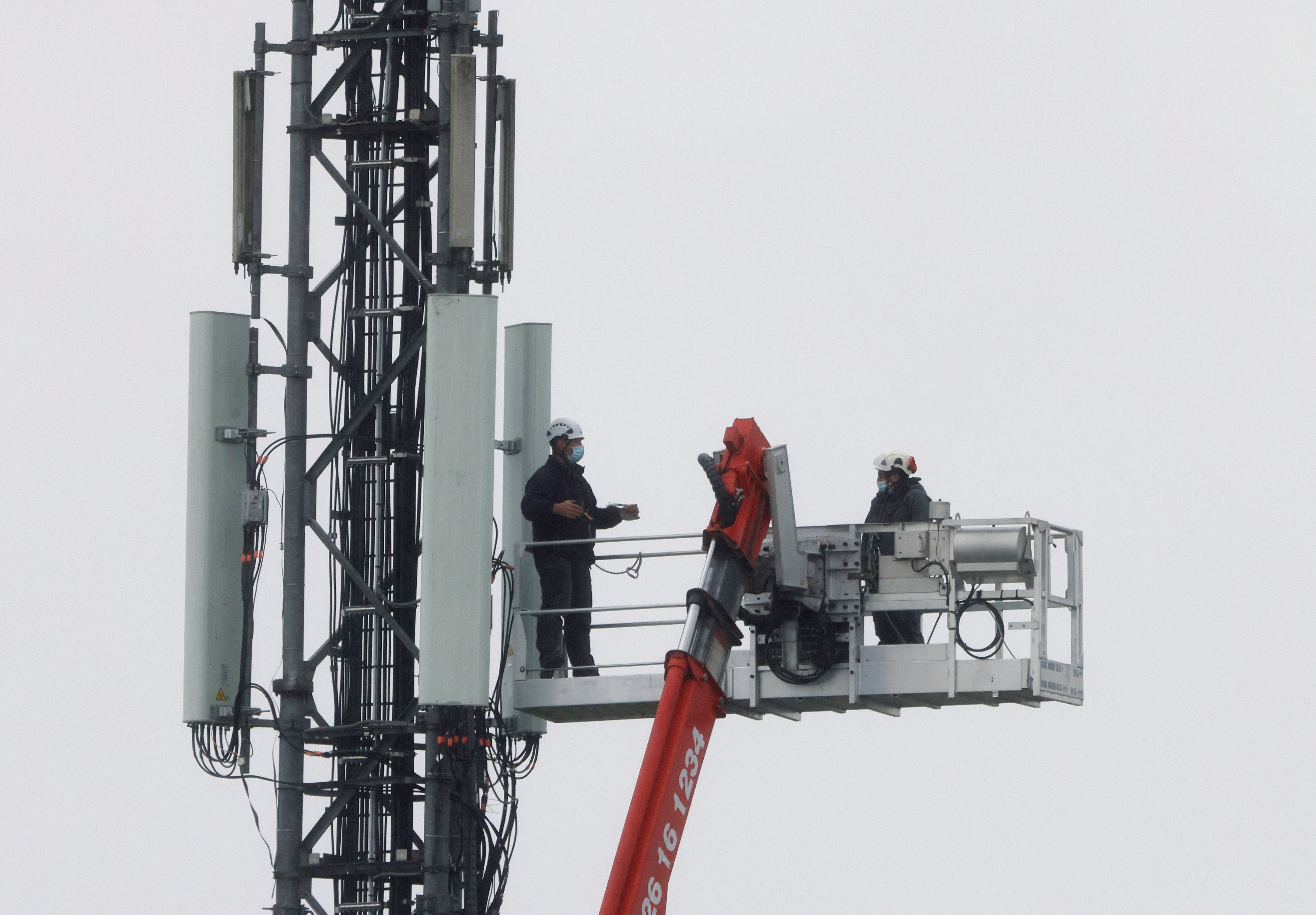 Technicians work at the top of transmitting antennas are seen on a mobile-phone network relay mast in Lambres-lez-Douai, France, September 30, 2020. REUTERS/Pascal Rossignol
