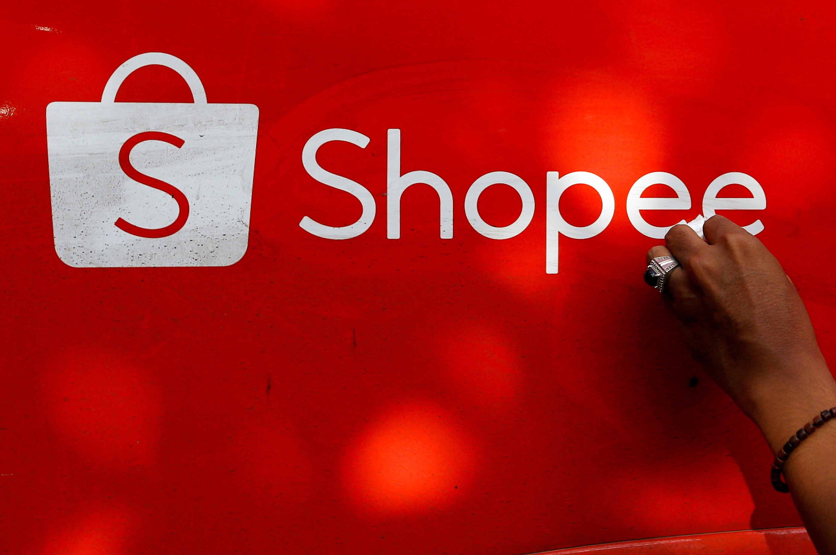 A worker wipes the door of a car with the sign of Shopee, an Indonesian e-commerce platform, in Jakarta