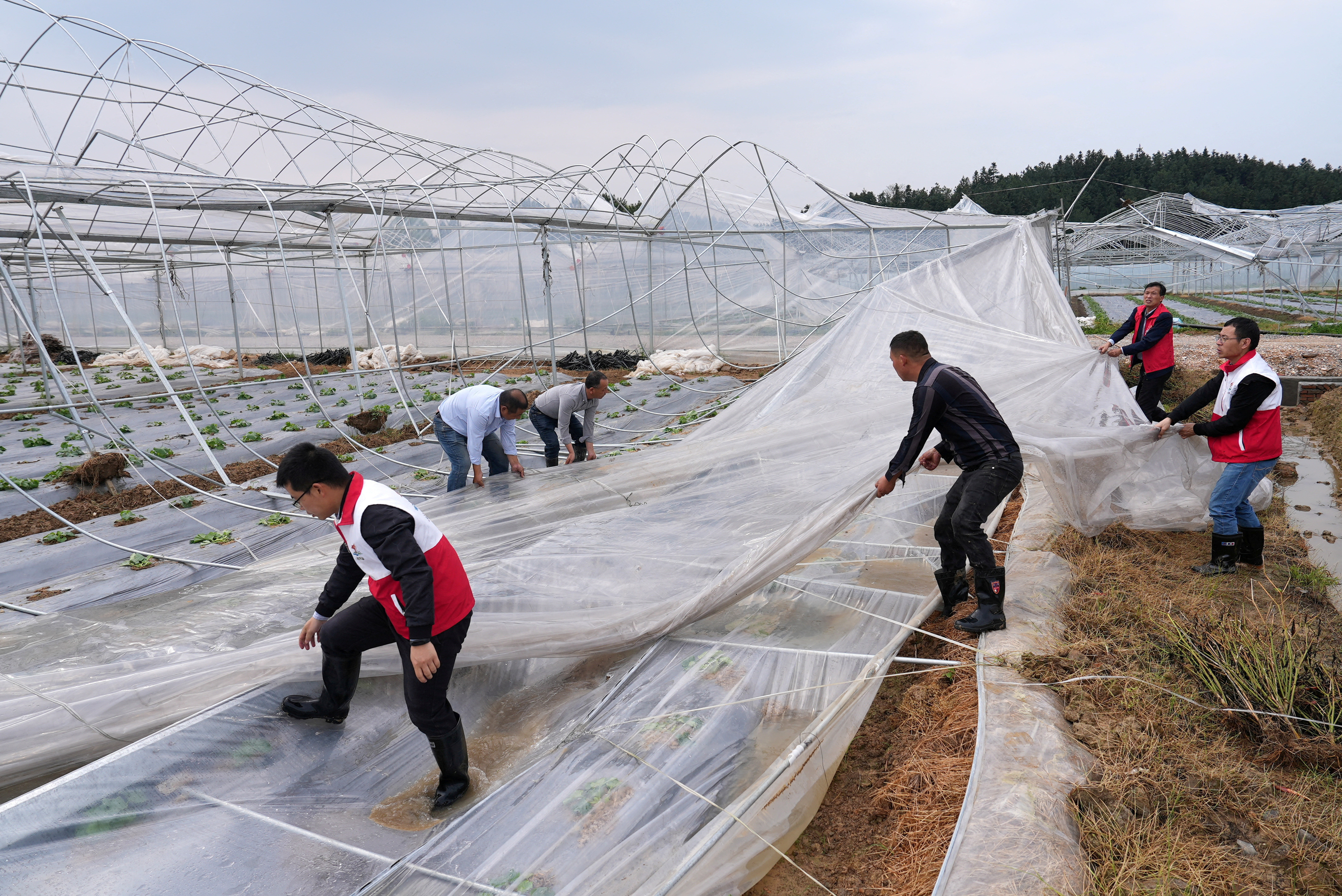 Men clean up a damaged tent in Yongfeng county