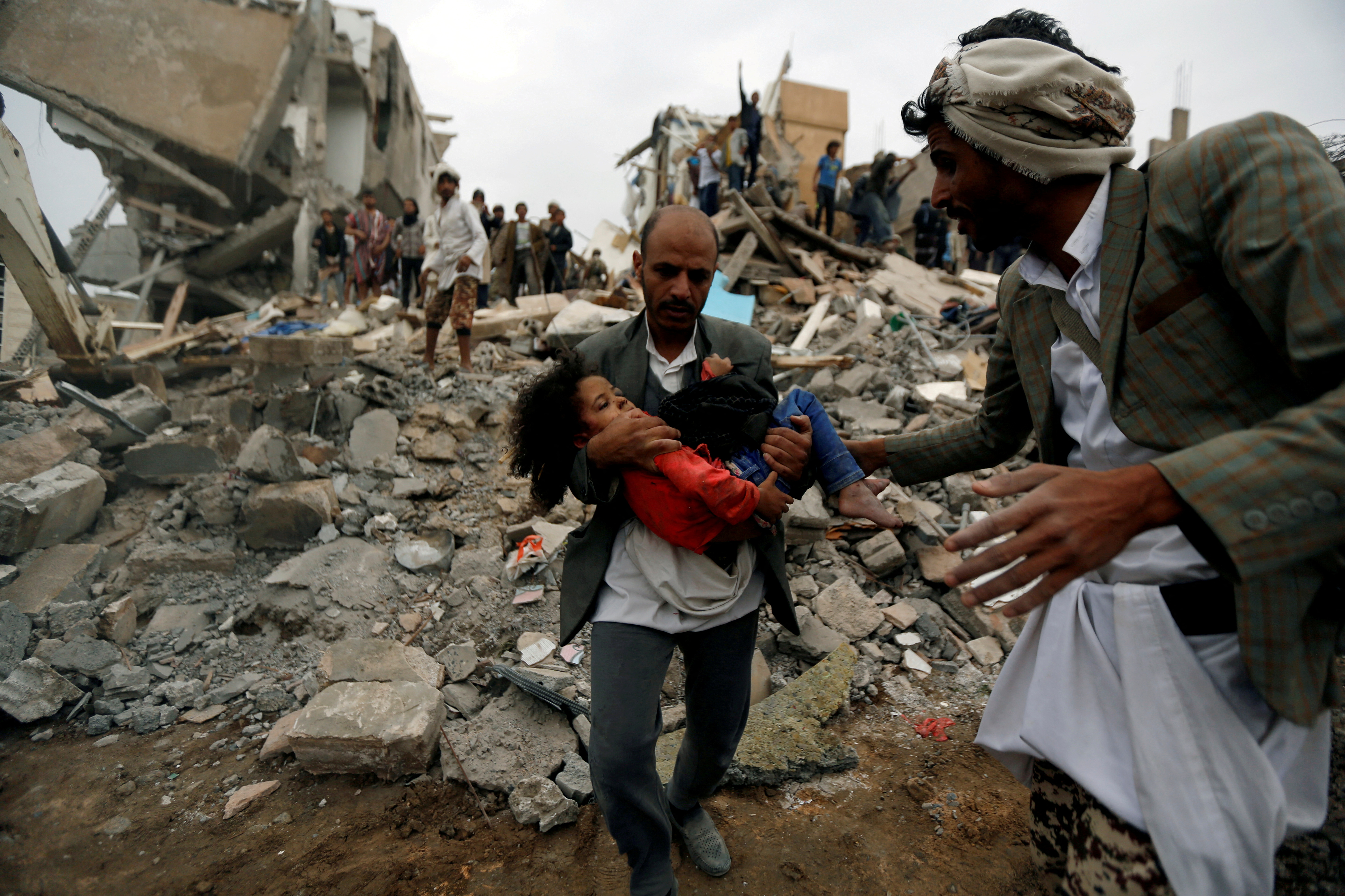 Man carries an injured girl rescued from the site of a Saudi-led air strike, in Sanaa