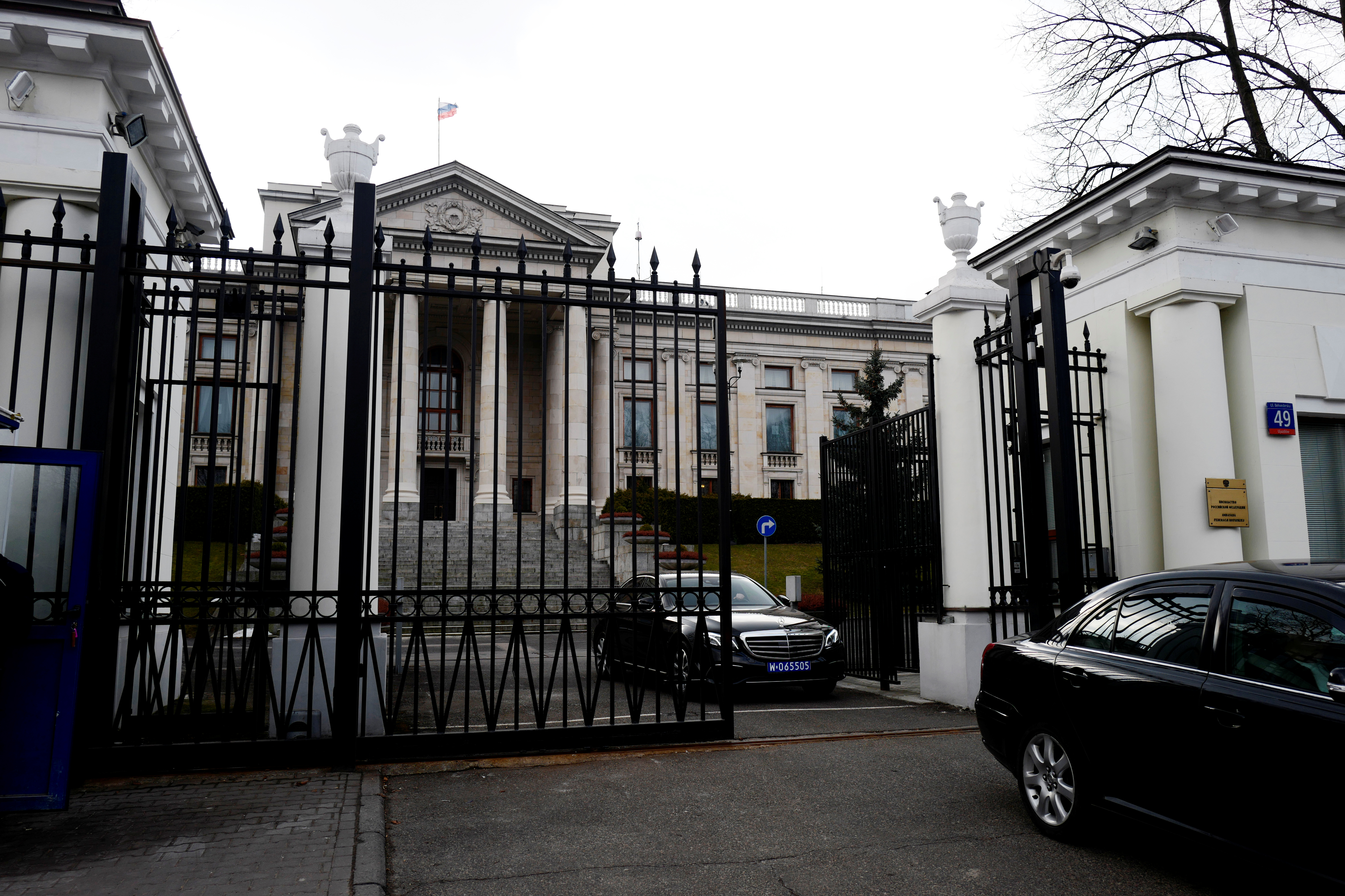 Cars leave through the gate of the Russian embassy building in Warsaw
