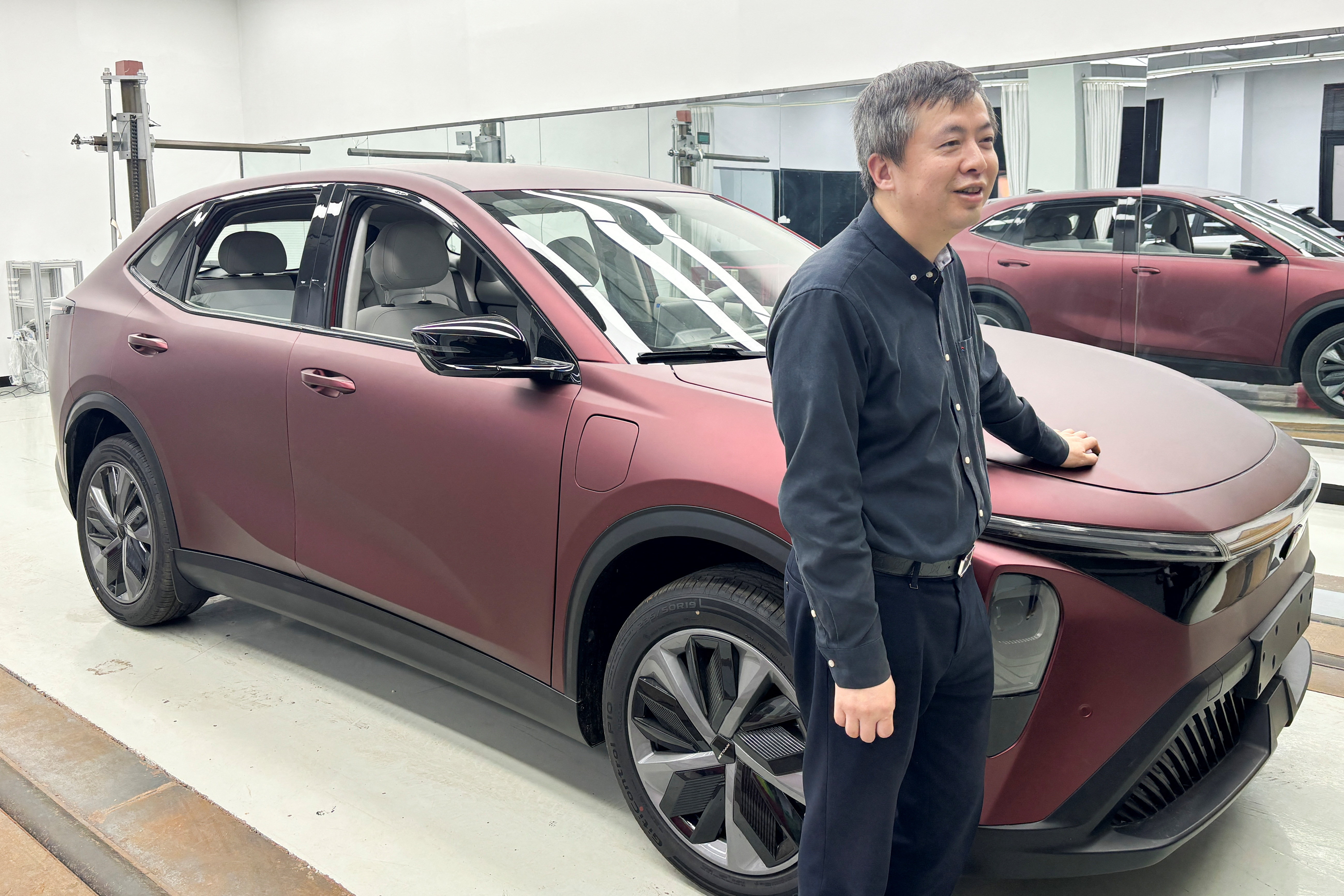 Wang Xun, founder and chairman of the auto design and engineering firm Launch Design, poses for a picture next to a prototype vehicle at the company's office in Shanghai