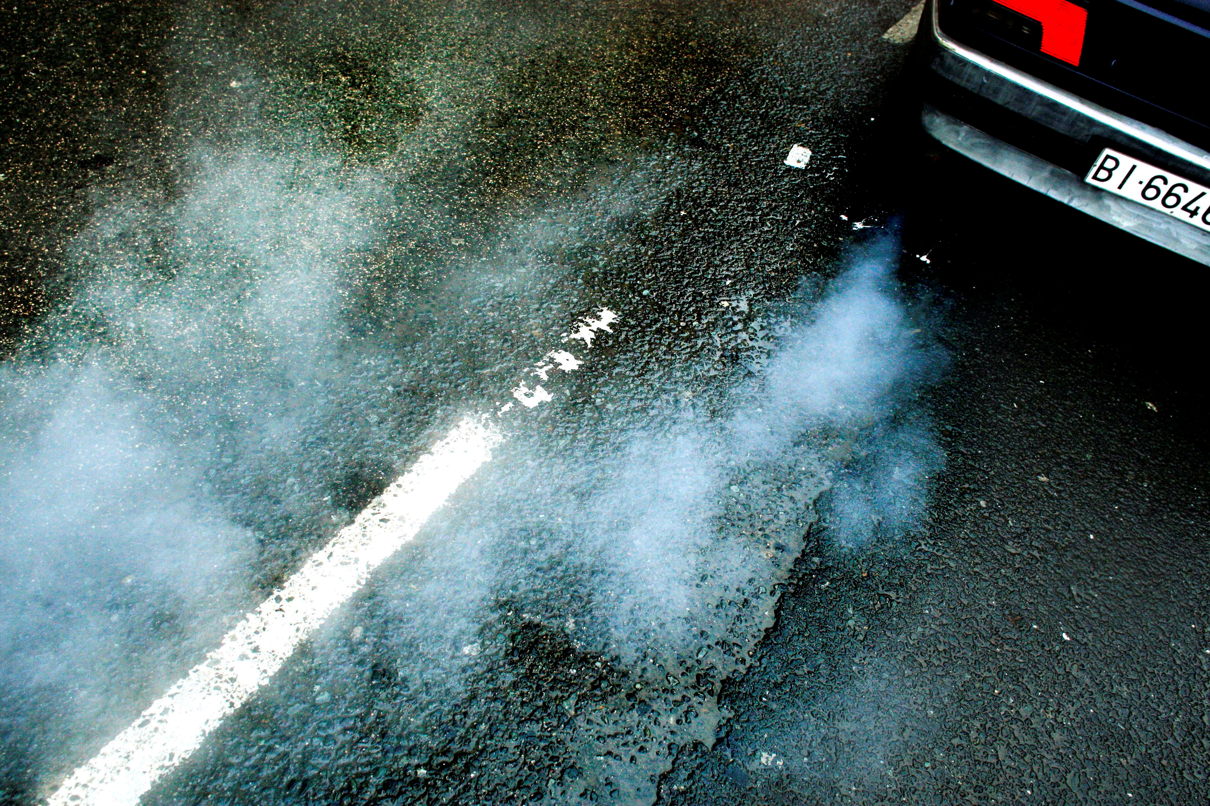 A car produces smoke from its exhaust as it pulls away in Guernica