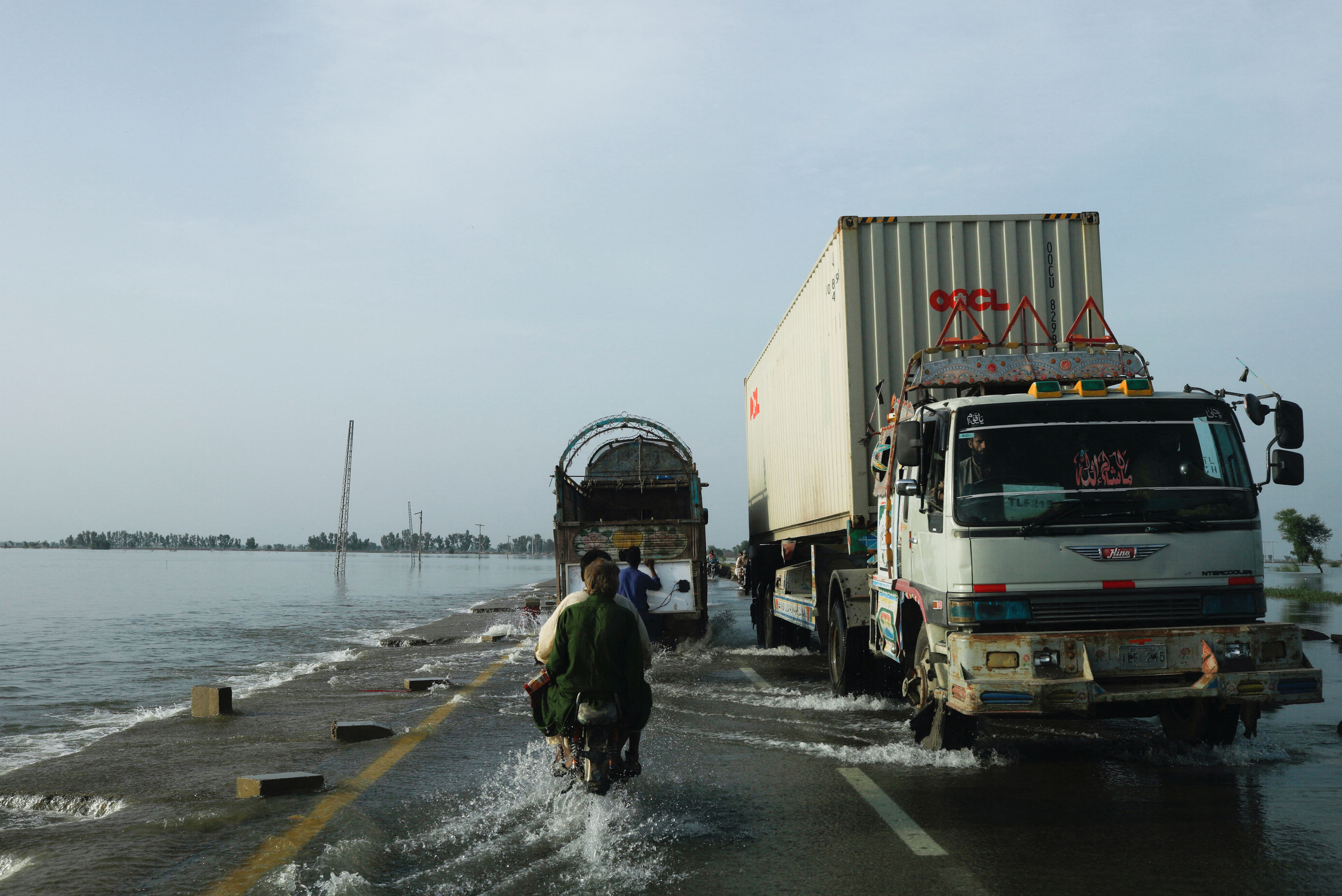 Vehicles move along a flooded road, following rains and floods, in Mehar