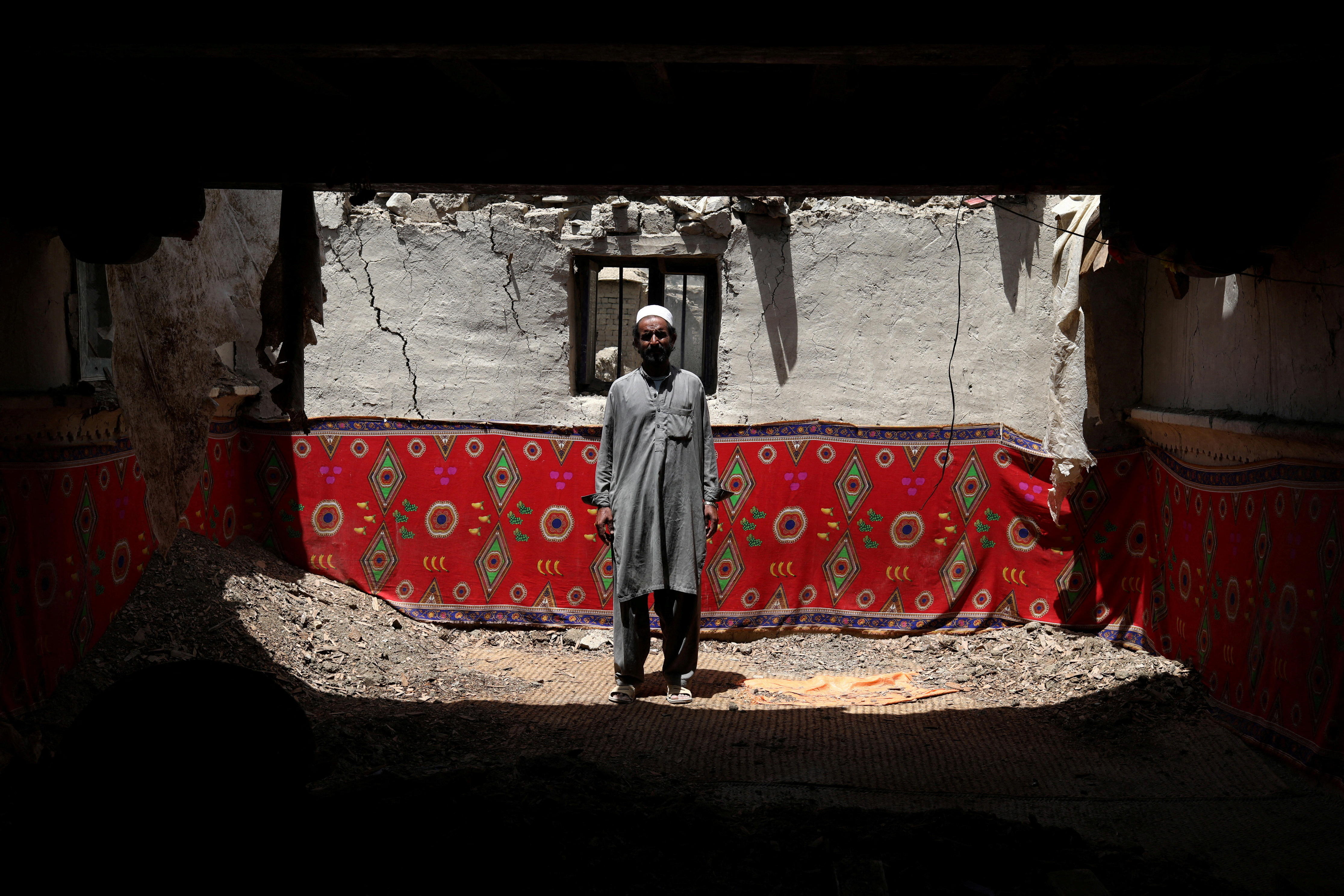 Ahmad Vali poses for a picture inside his house that was damaged by an earthquake in Gayan