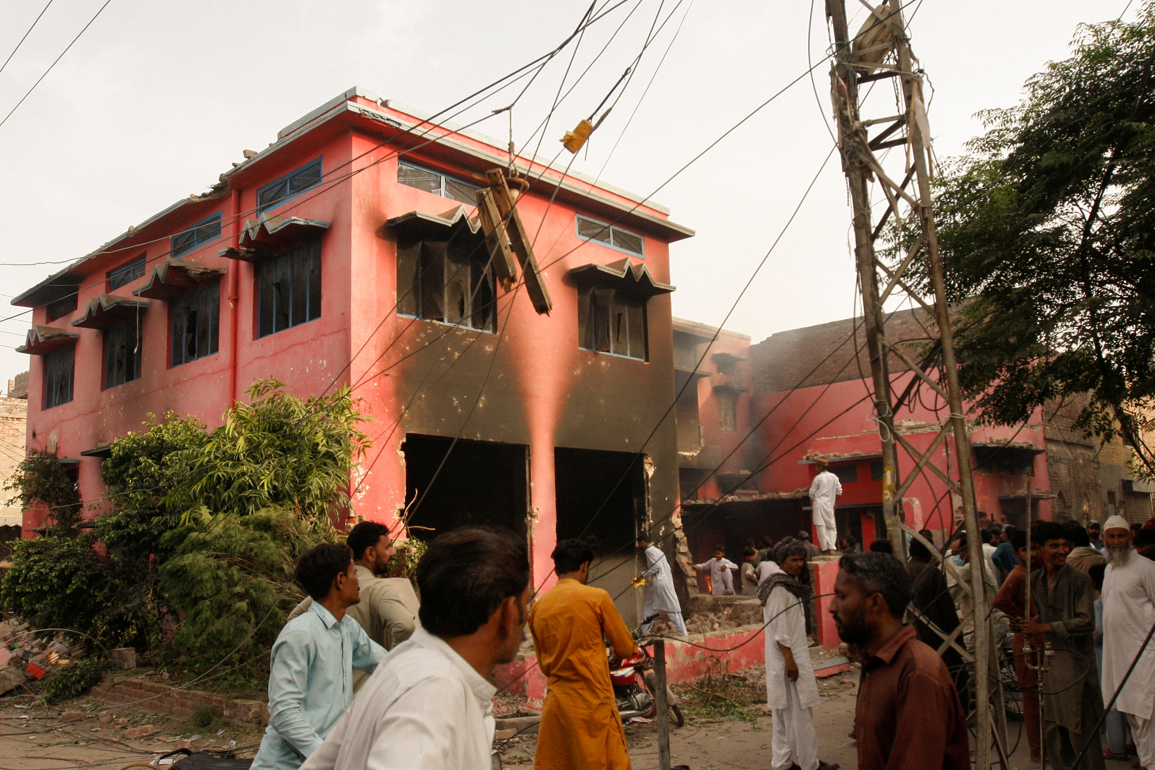 People gather at a church building vandalized by protesters in Jaranwala