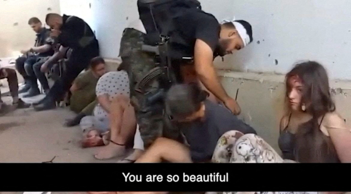 A Gazan militant binds the hands of Gilboa as other female hostages who are Israeli soldiers including Ariev sit on the ground during their capture at Nahal Oz military base