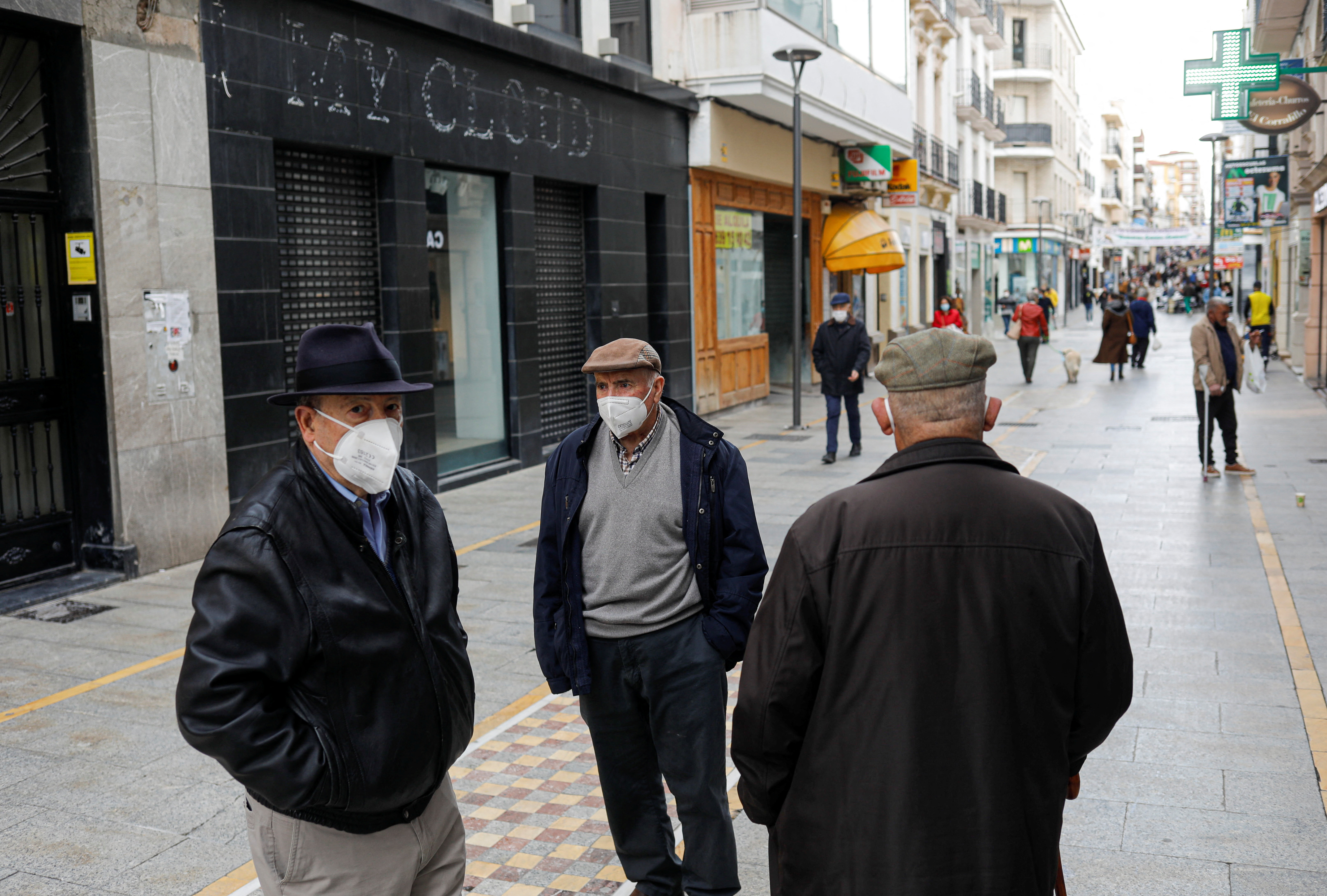 Pensioners wearing protective face masks due to COVID-19 pandemic chat in Ronda